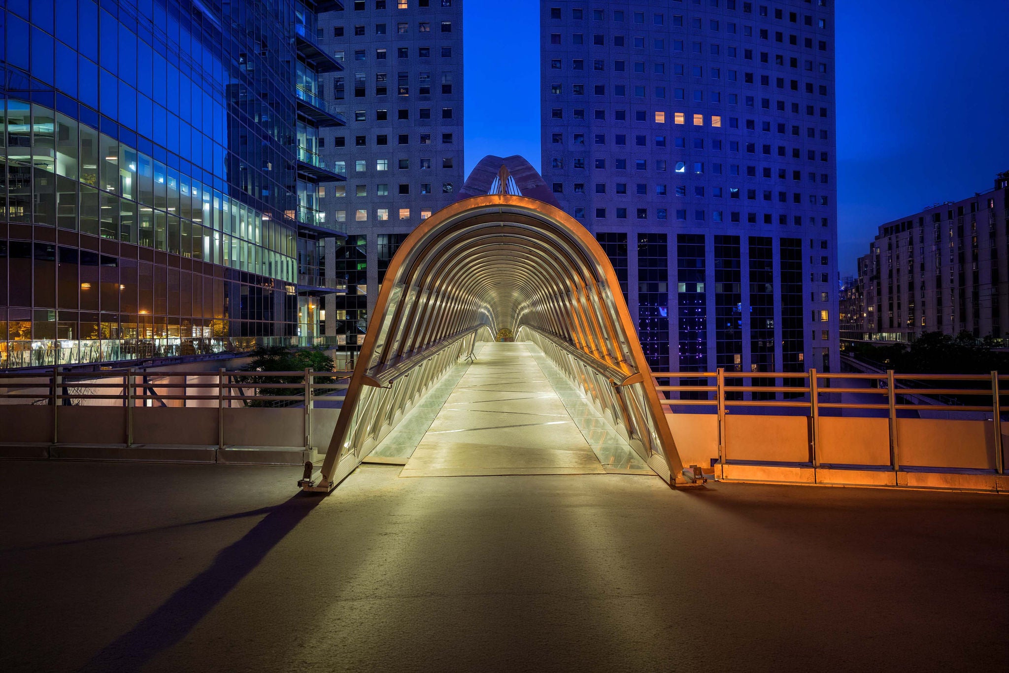 illuminated abstract glass skywalk at dusk, La Defense, Paris, France