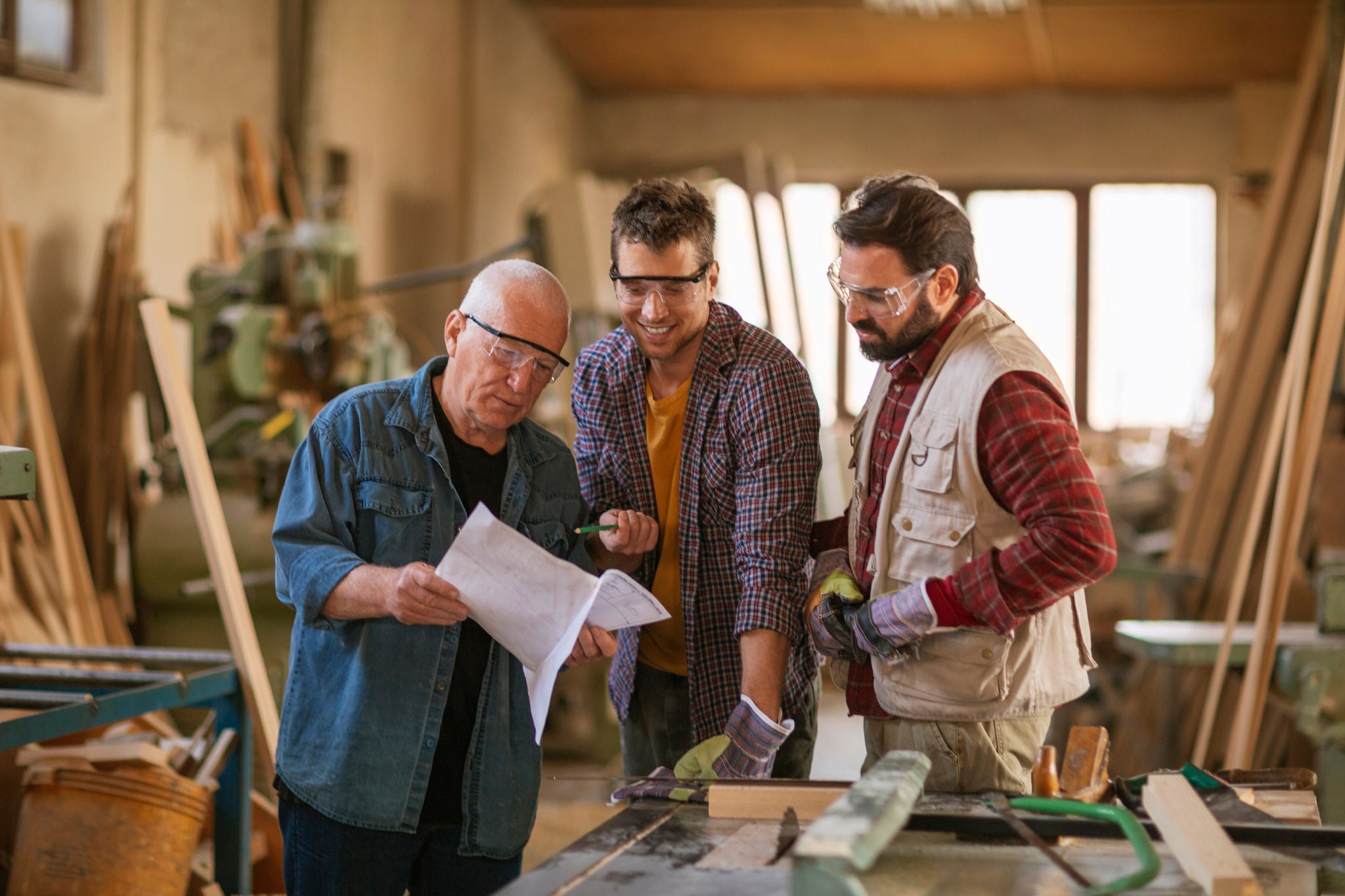 Multigenerational group of carpenters working together in a woodworking workshop