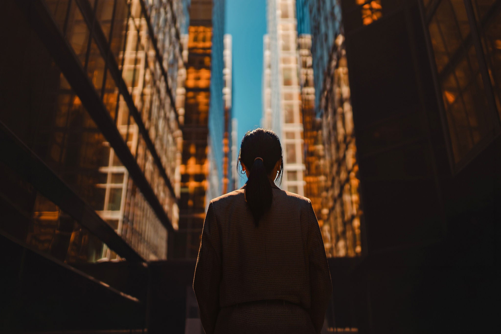 Looking towards blue sky in the city. Concept of female leadership and entrepreneurship. Woman's empowerment. Career achievement and success