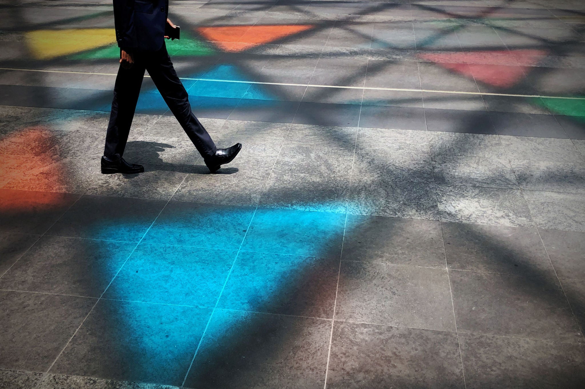 Personne marchant sur sol carre avec reflets colores