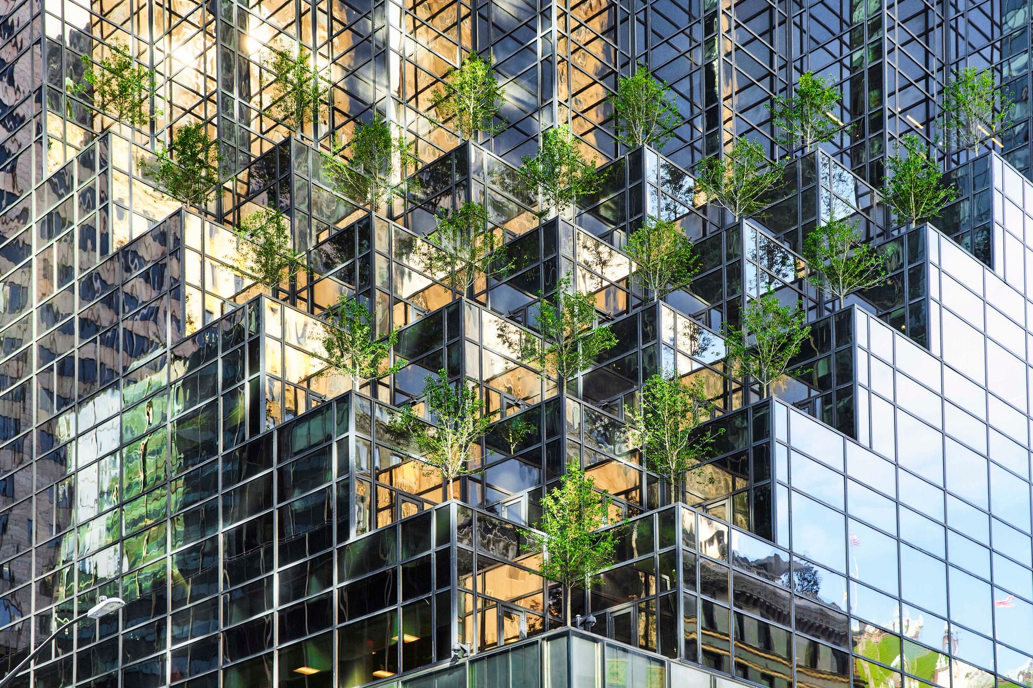 High angle view of a mirrored skyscraper with a modern trees installation on the facade, New York, USA