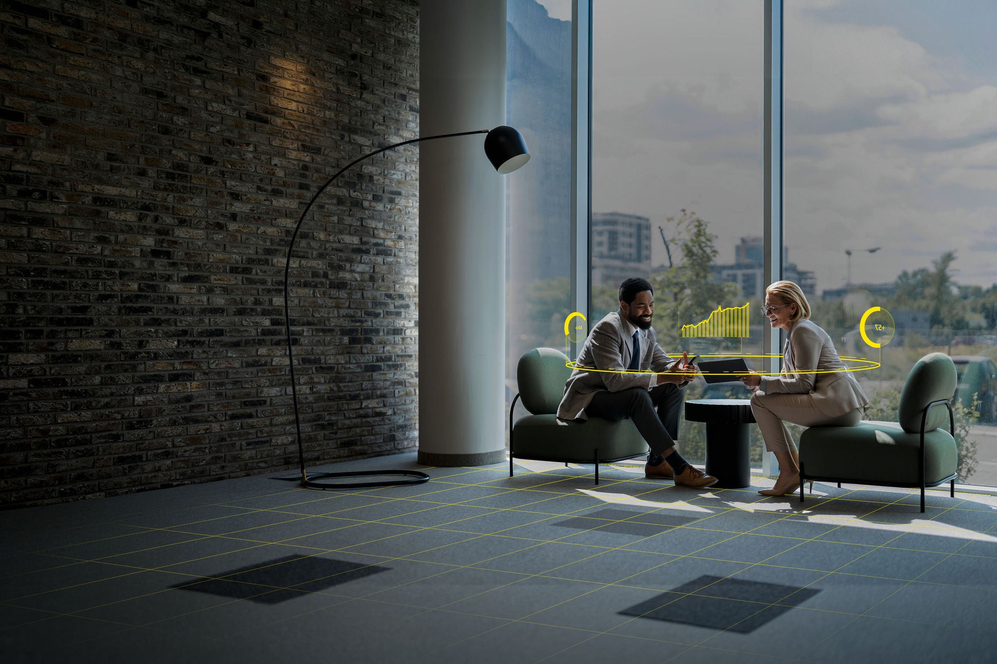Two business people sitting in armchairs and discussing work using digital devices in a modern office