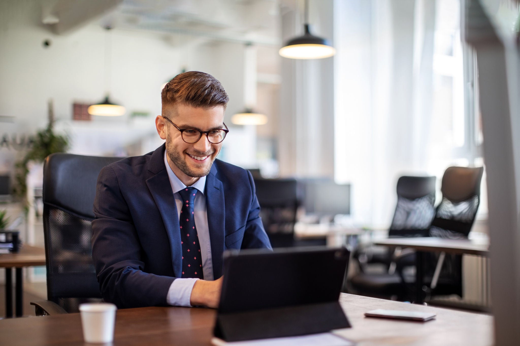Corporate workspace scene with a professional using a laptop in a bright modern office.