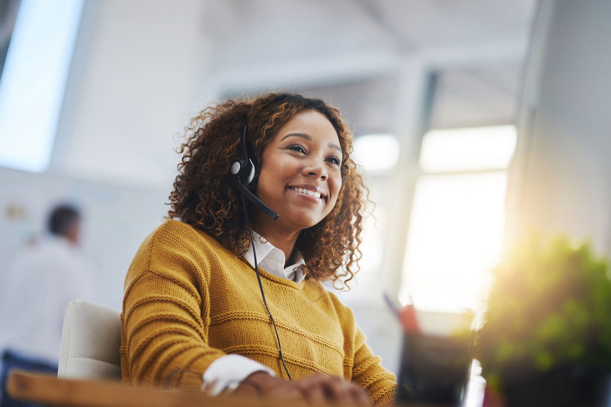 Smiling call center agent wearing headset assisting customers with support, consultation and help desk services daily.