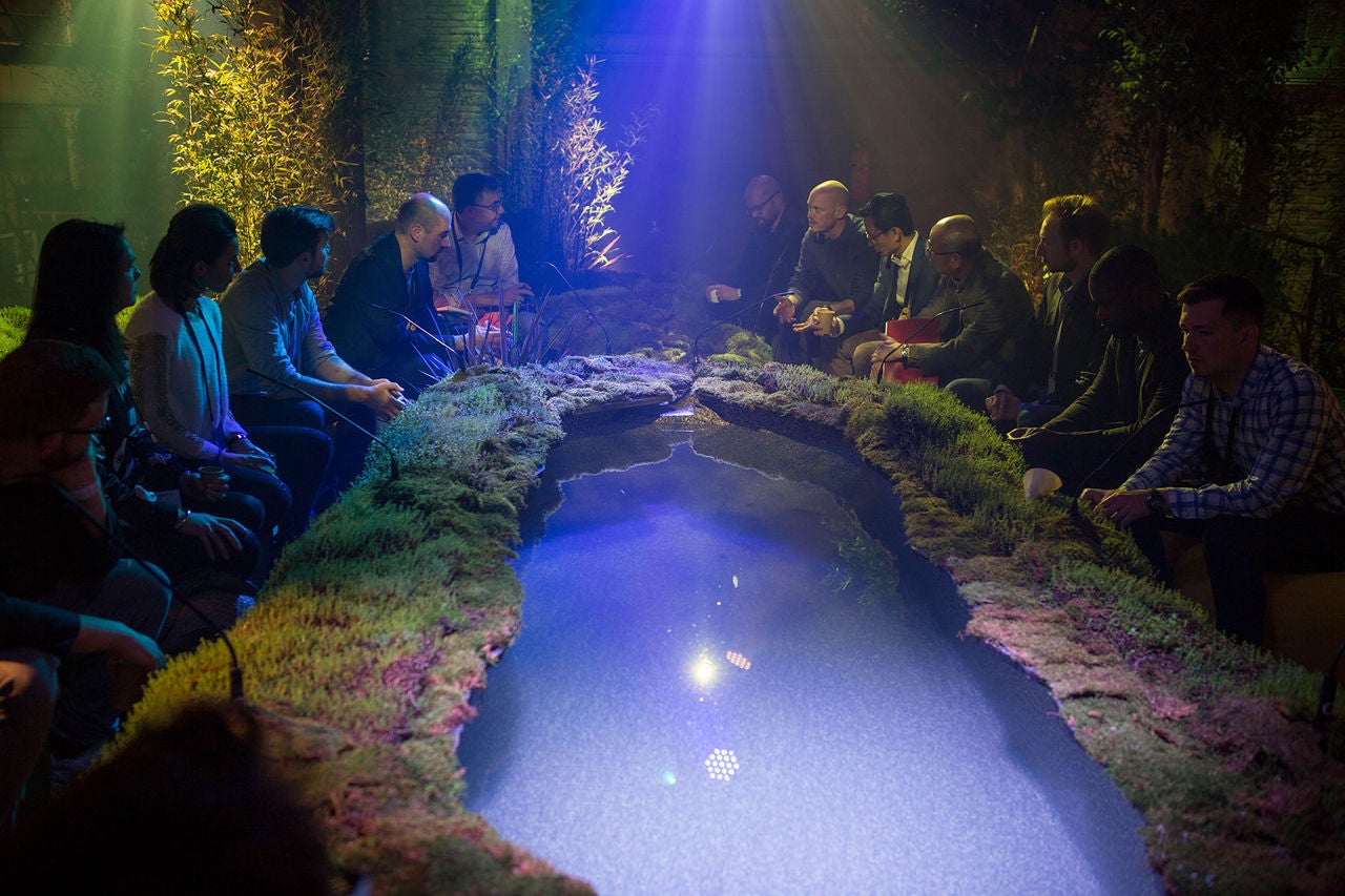 Attendees sit around a pond at Innovation Realized