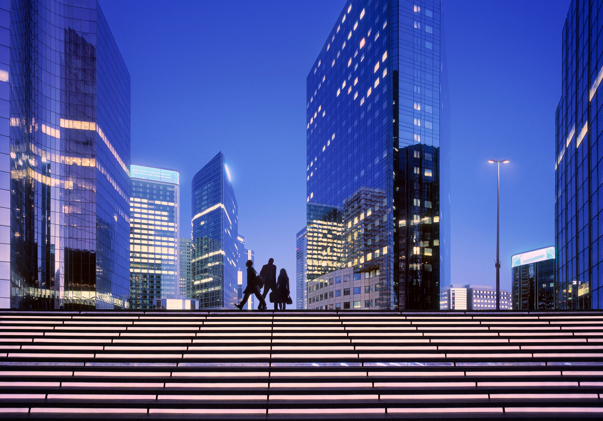 Morning image with businesswoman and businessmen arriving at modern business district.