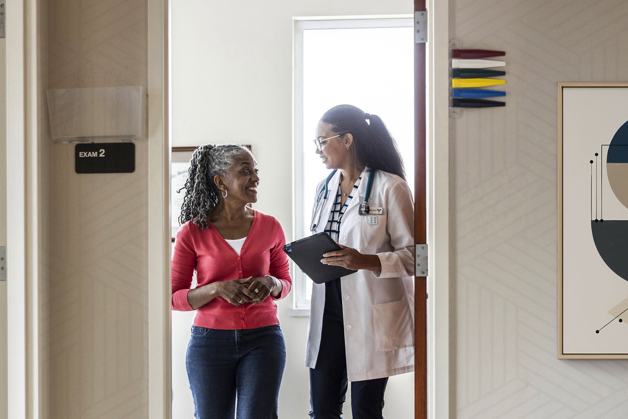 Female doctor talking with senior woman in doctor's office hallway