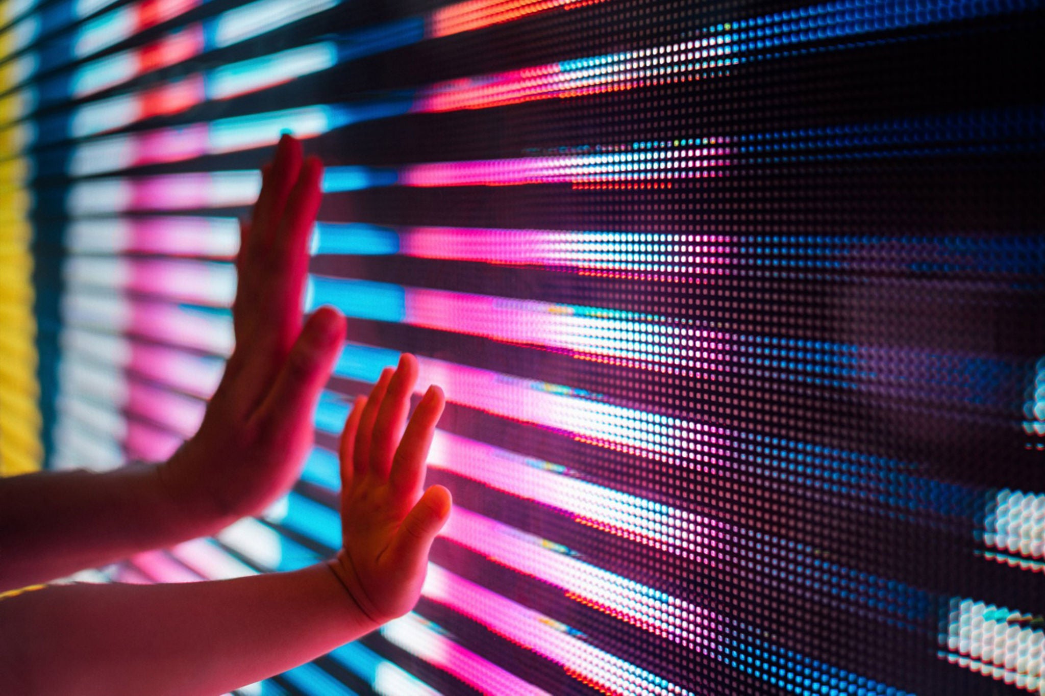 Close up of a mother and kids hand touching illuminated coloured led display screen