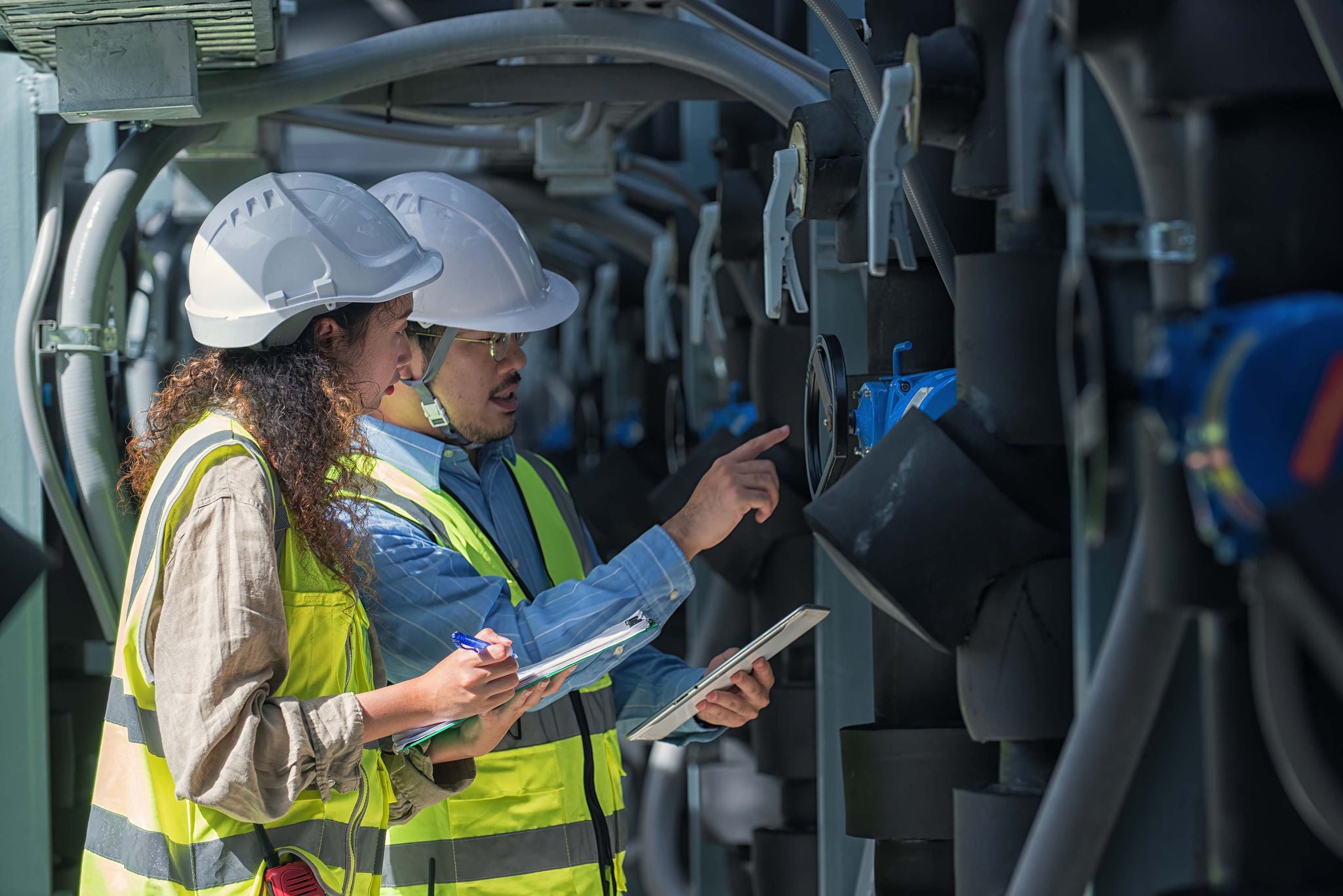 Engineers inspecting industrial piping and equipment at a processing facility