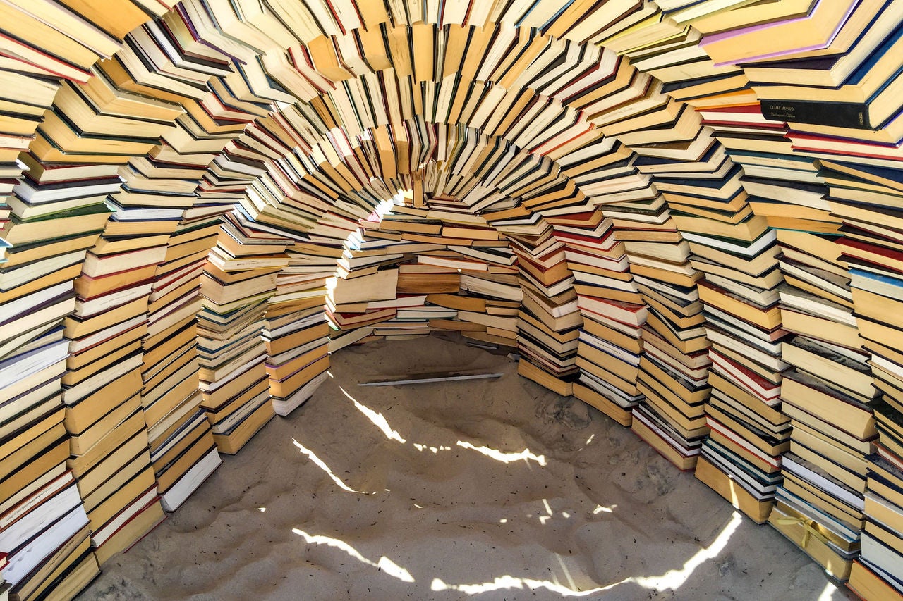 Tunnel formé par des livres empilés créant une arche de pages
