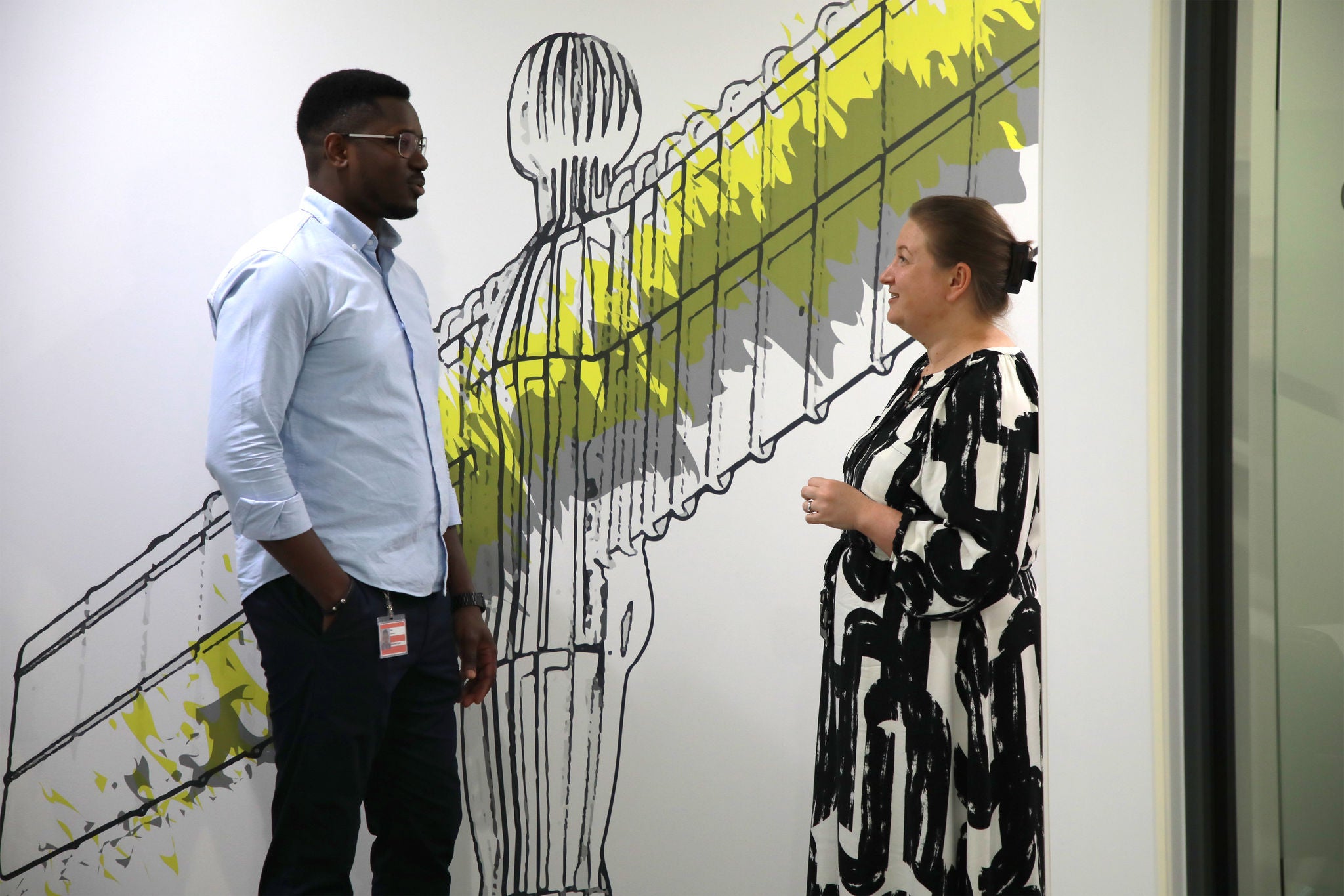 Two colleagues talking in front of a mural