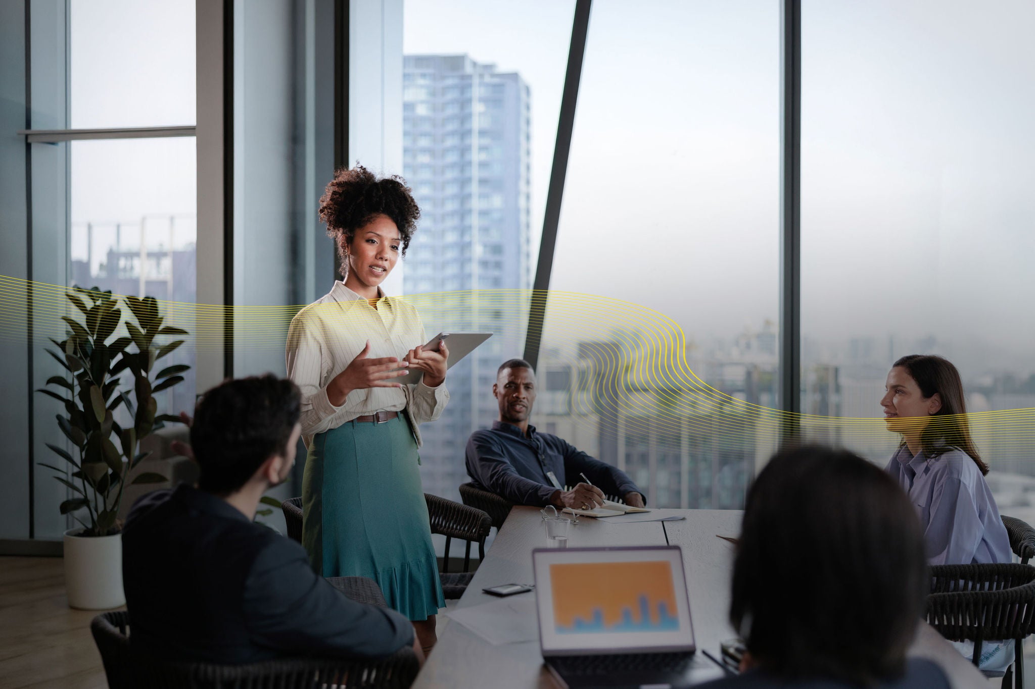 Person presenting to colleagues during a meeting in a modern office conference room.