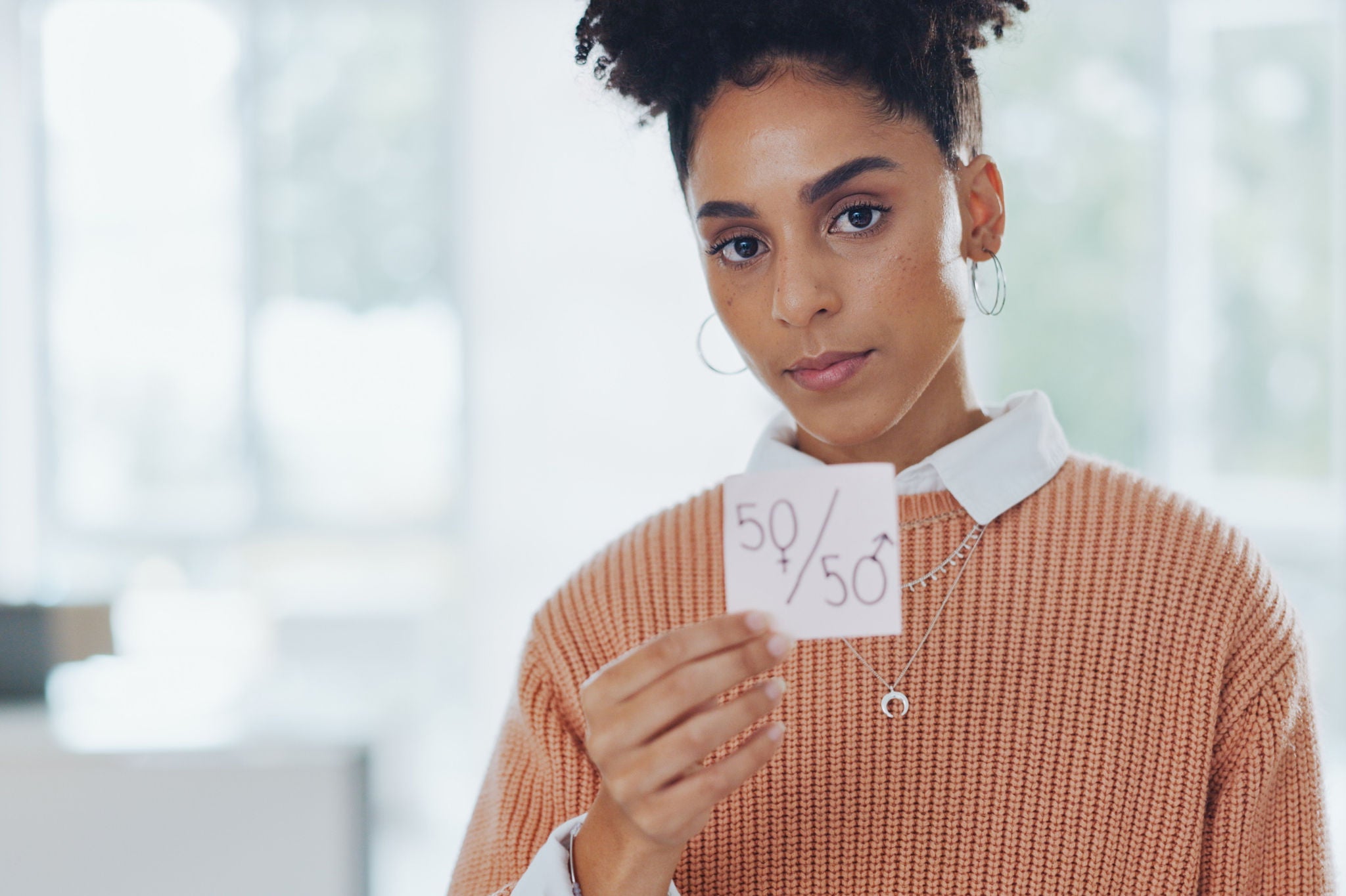 Personne tenant un papier montrant un partage 50 50 dans un espace lumineux.