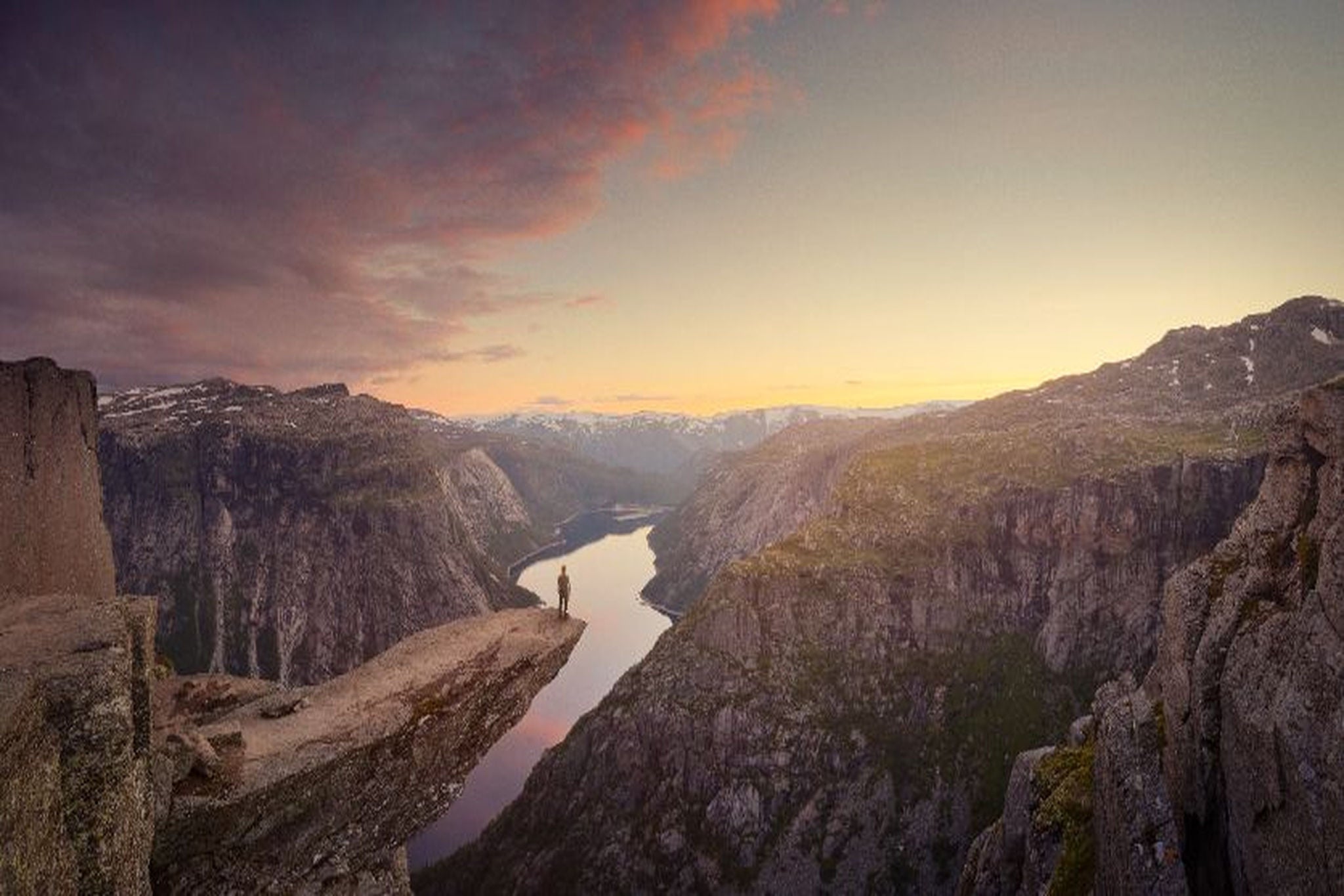 Person standing on a cliff overlooking a mountain valley.