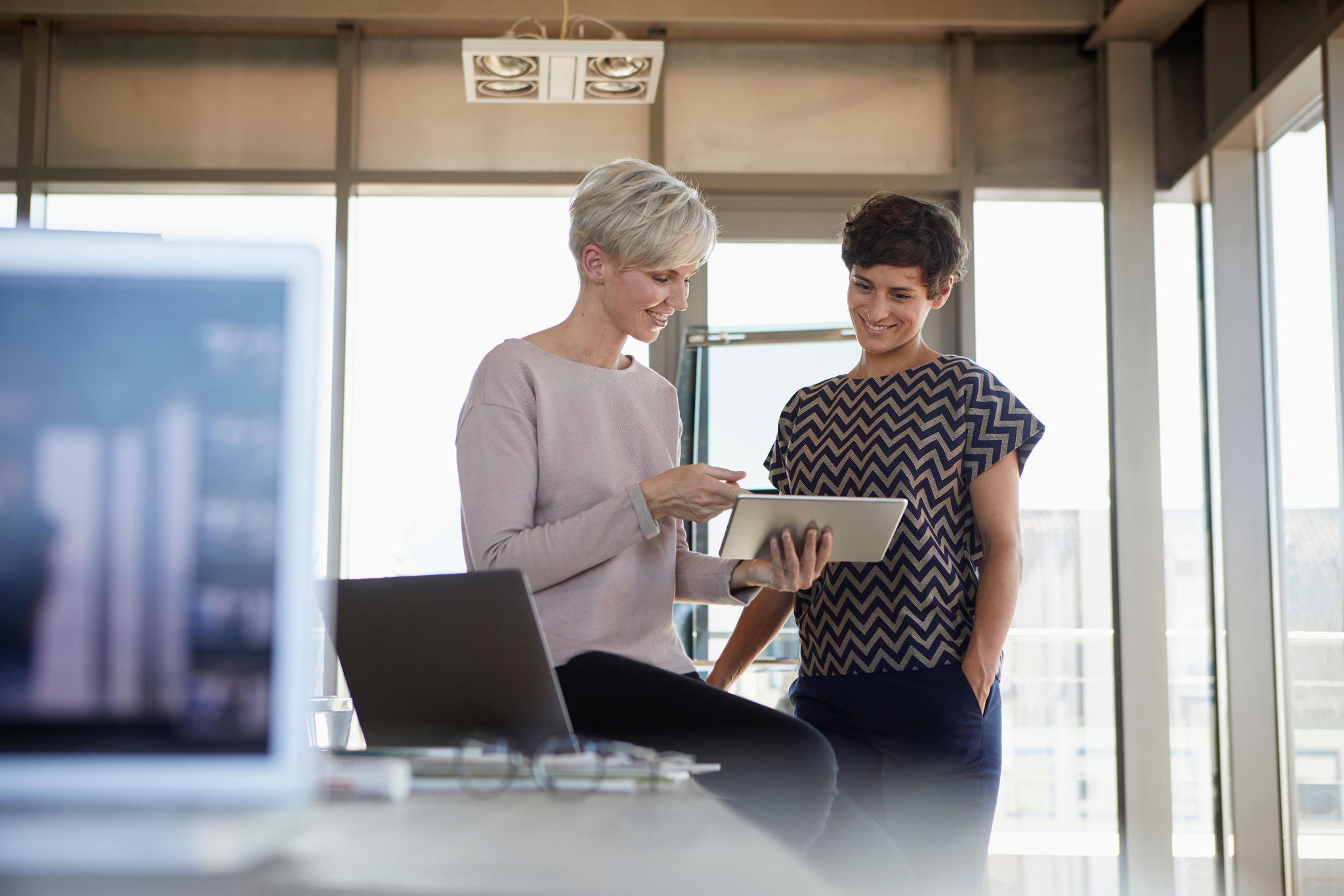 Smiling businesswomen sharing tablet in office