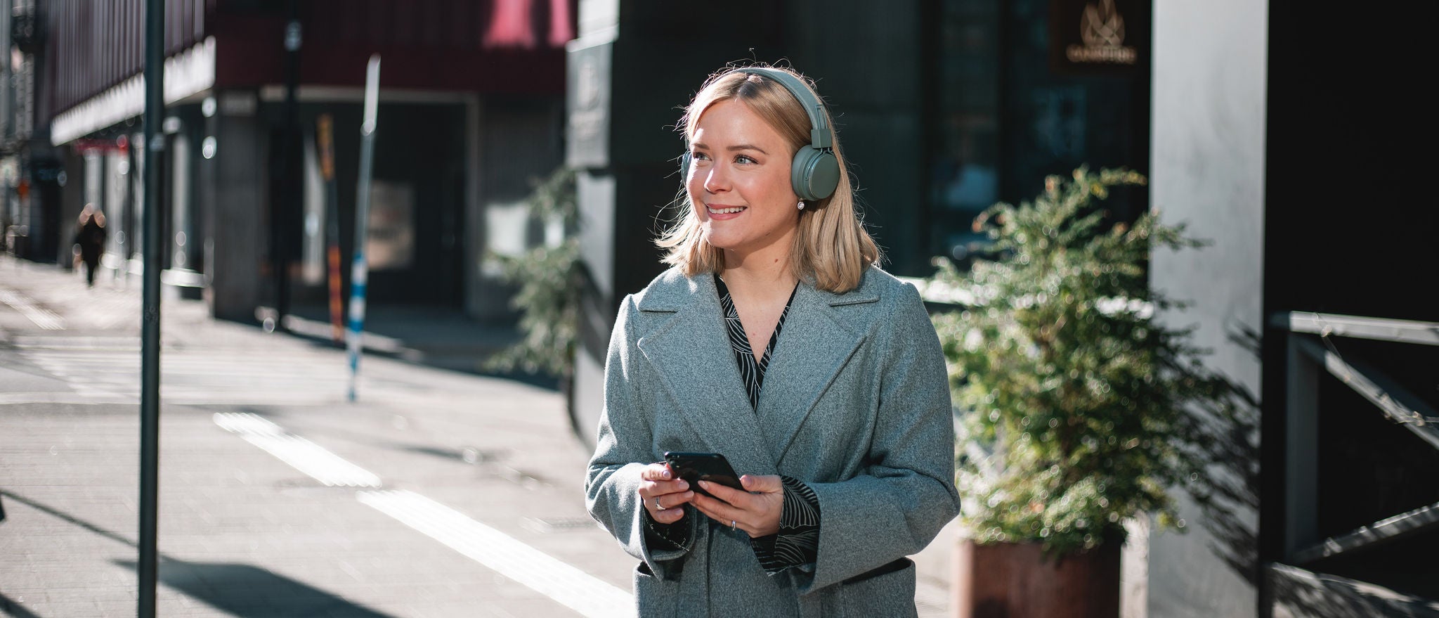 Professional using smartphone with headphones while walking in city