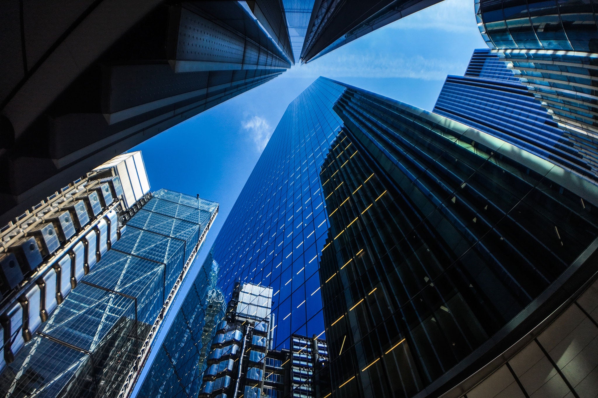 Modern glass skyscrapers viewed from below against a clear blue sky