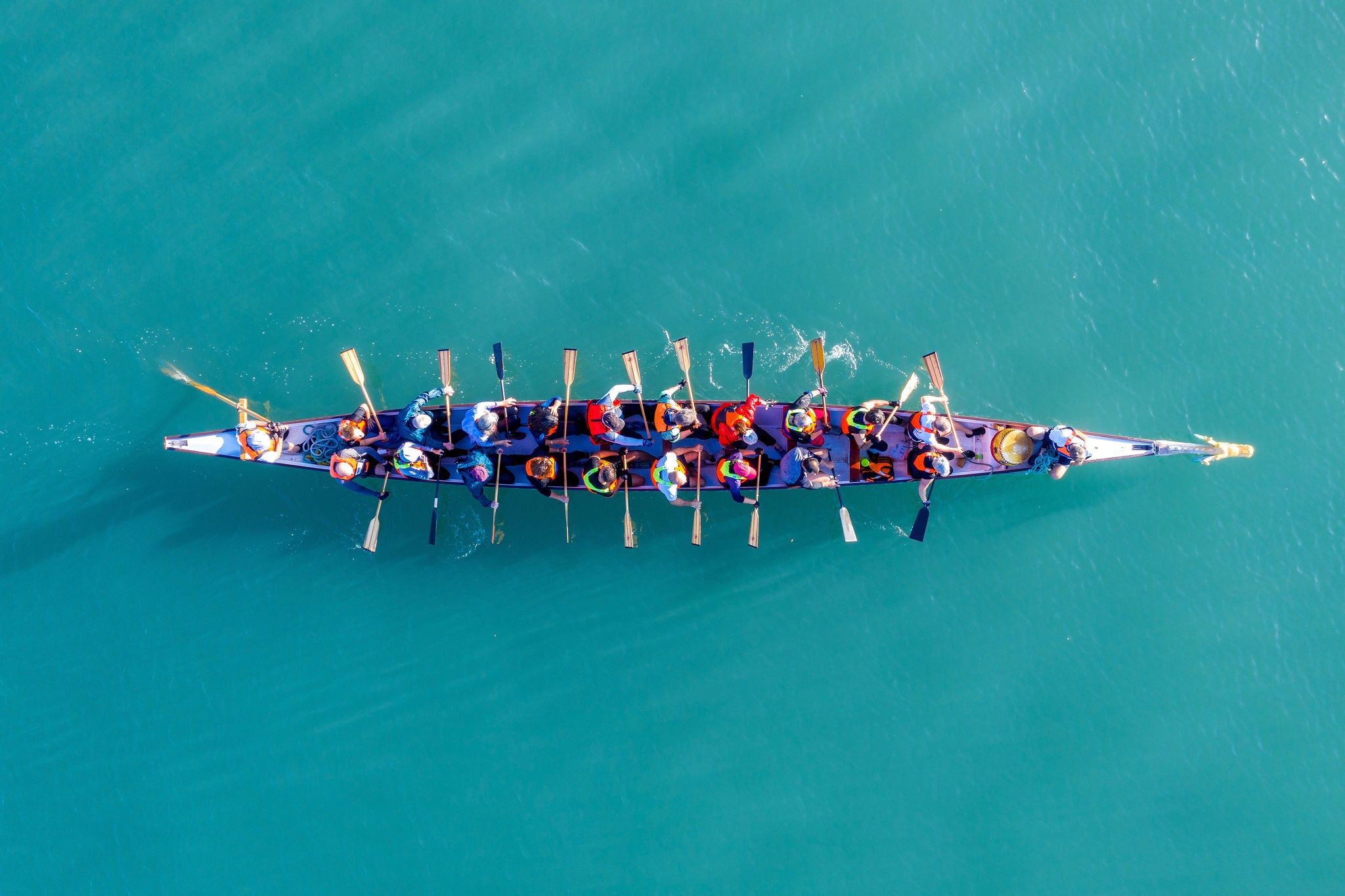 Aerial view of a team rowing a dragon boat on water