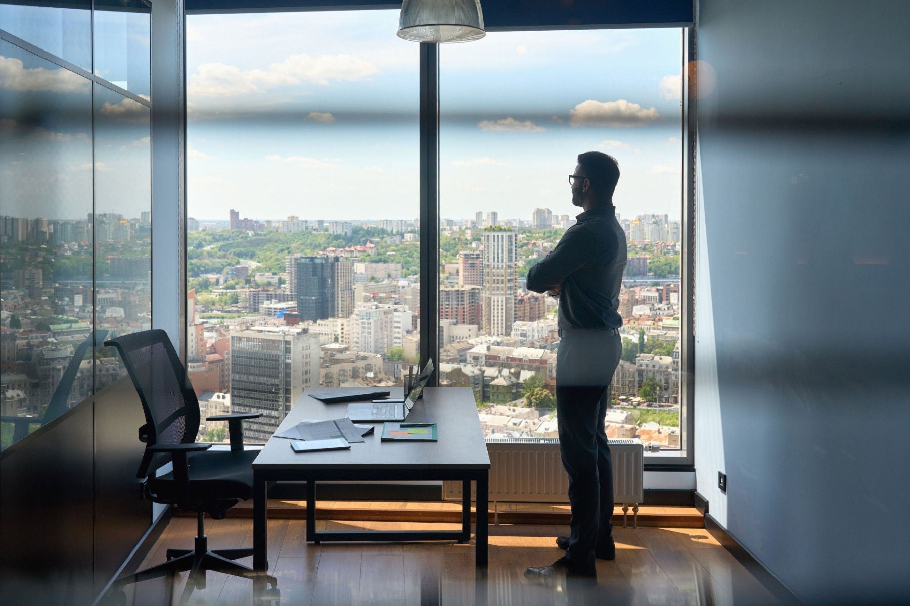 Silhouette of businessman standing in office with big-city capital urban view