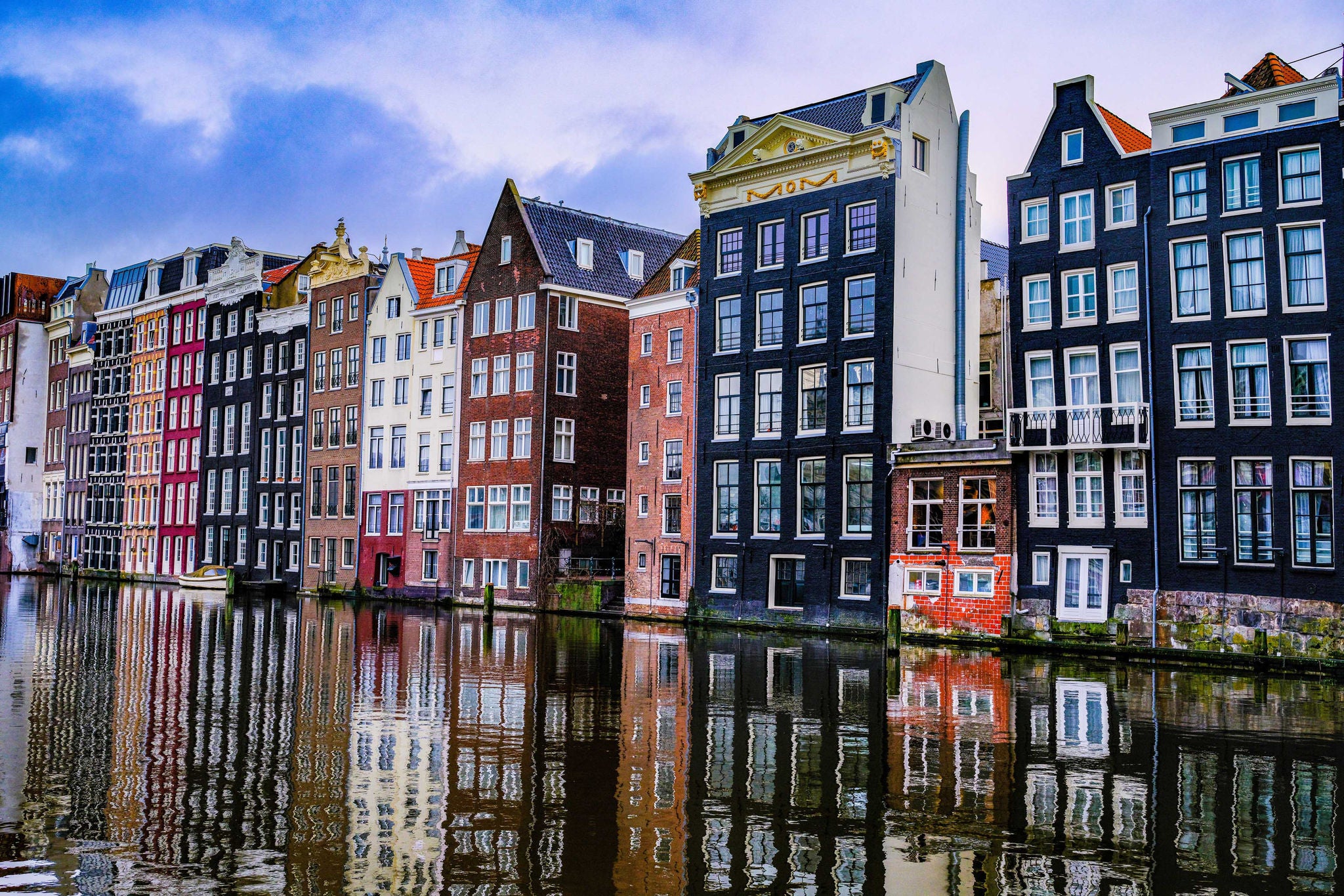 „De Dansende Huisjes“ (Die tanzenden Haeuser) am Damrak in Amsterdam – bunte, schmale Giebelhaeuser entlang des Kanals.