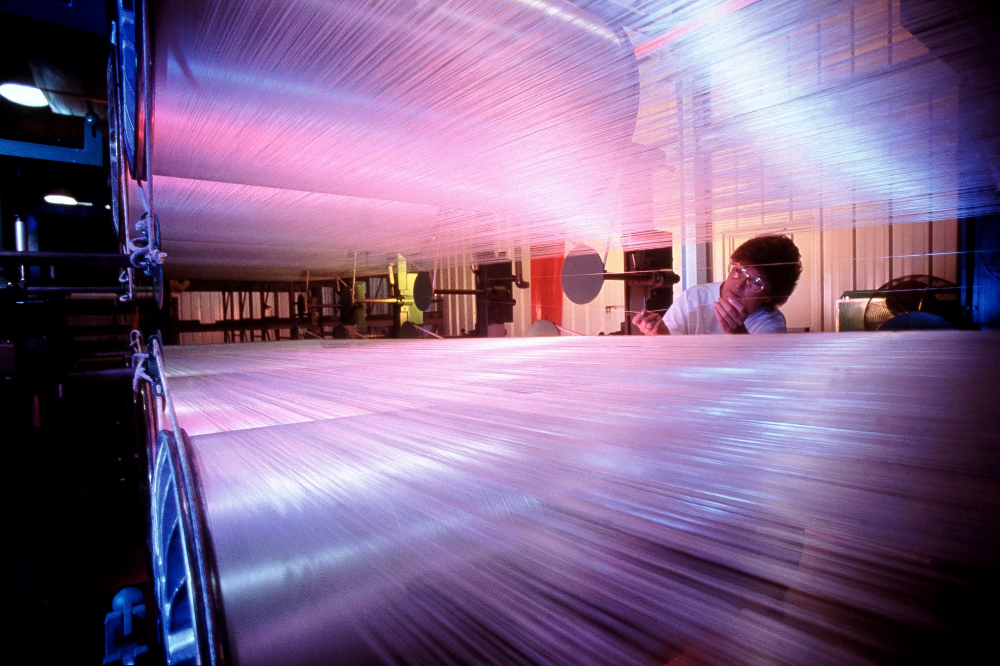Woman inspects threads during textile manufacturing