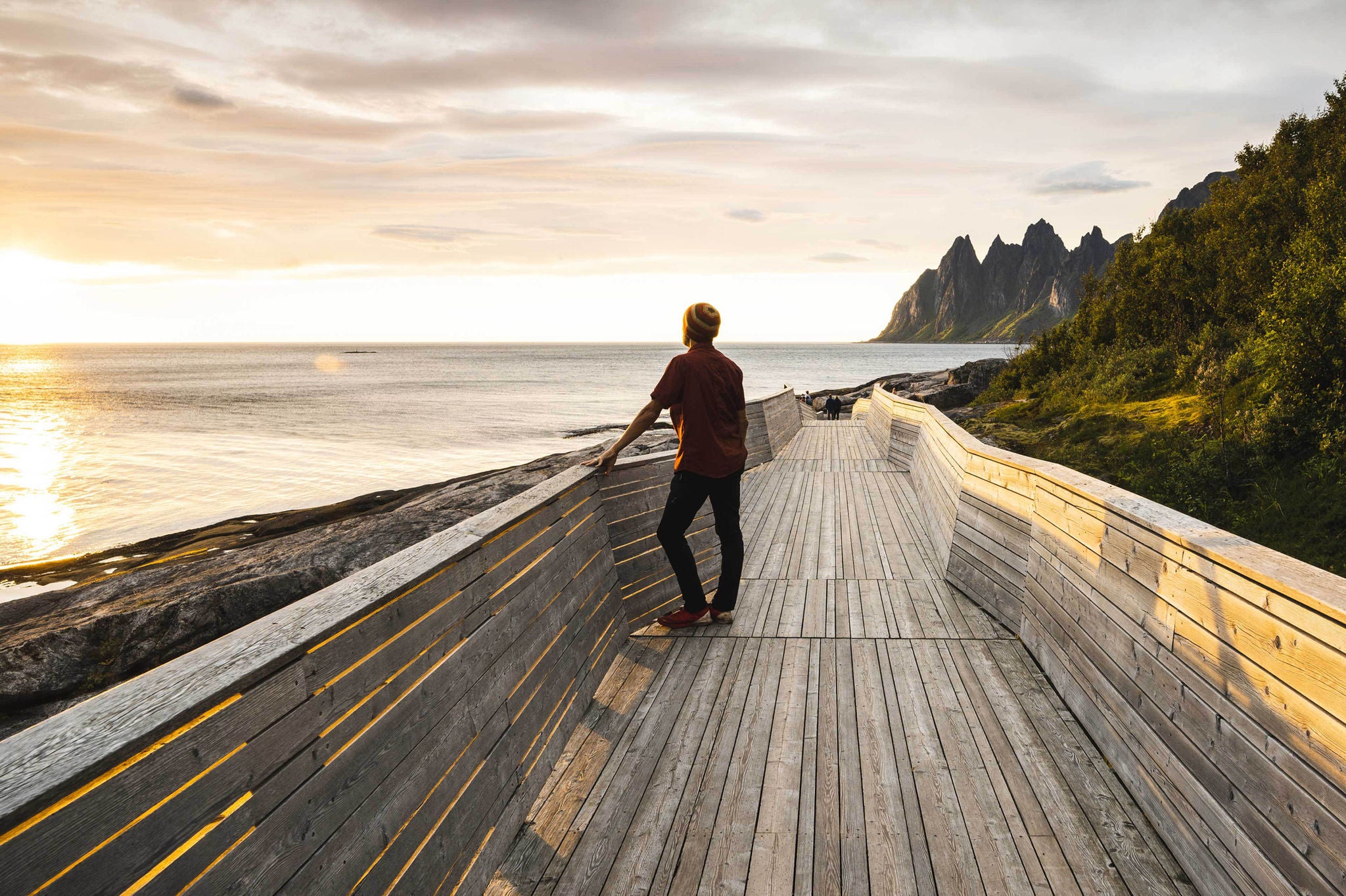 Person standing on a wooden pier watching sunset, Senja, Norway