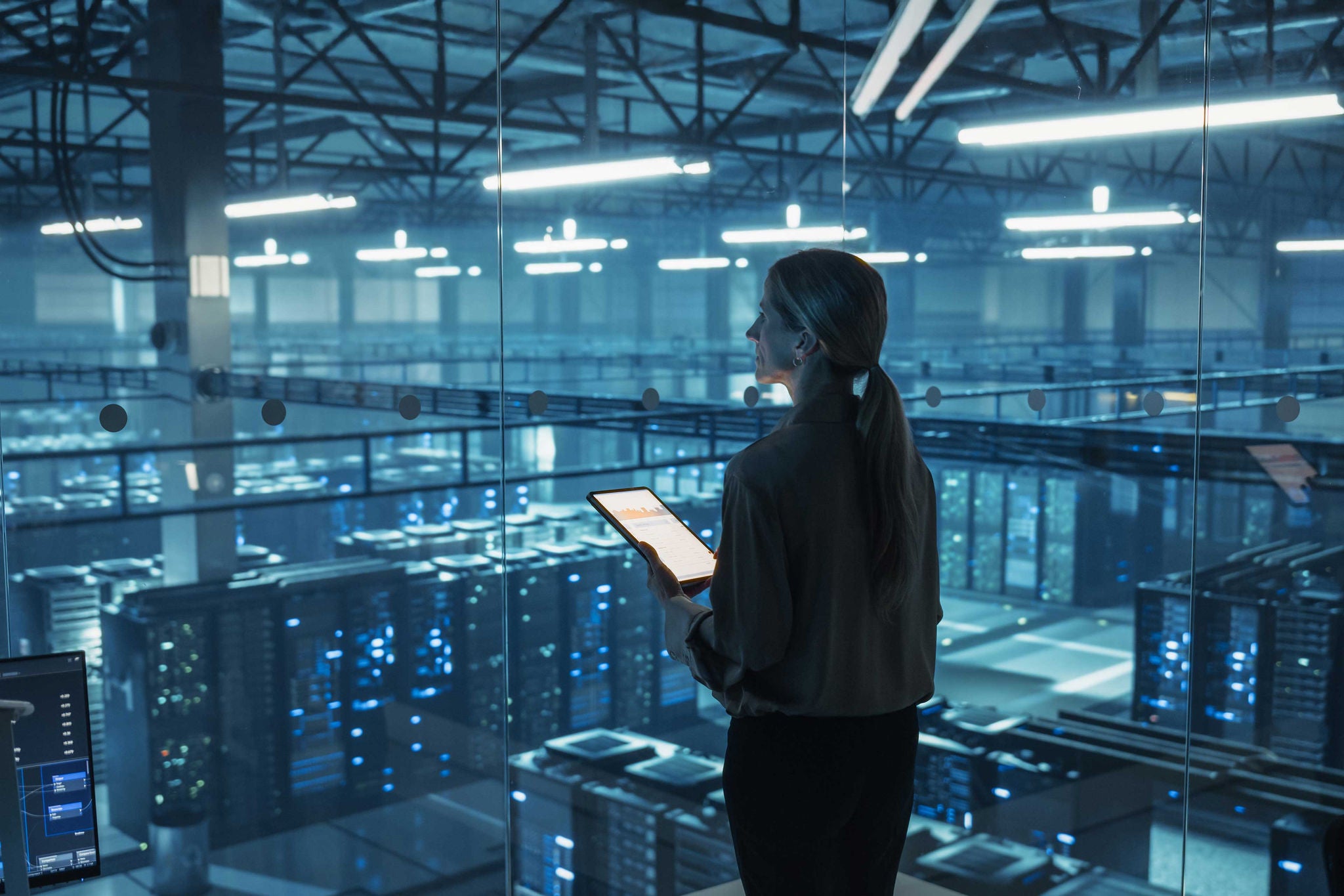 IT‑Ingenieurin überprüft Sicherheitsprotokolle auf Tablet in einem Rechenzentrum