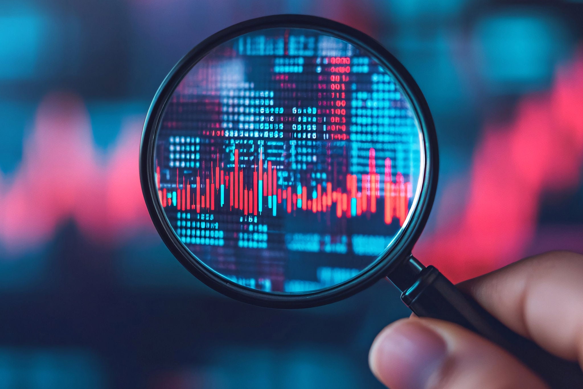 Magnifying glass focusing on digital data and stock market graph