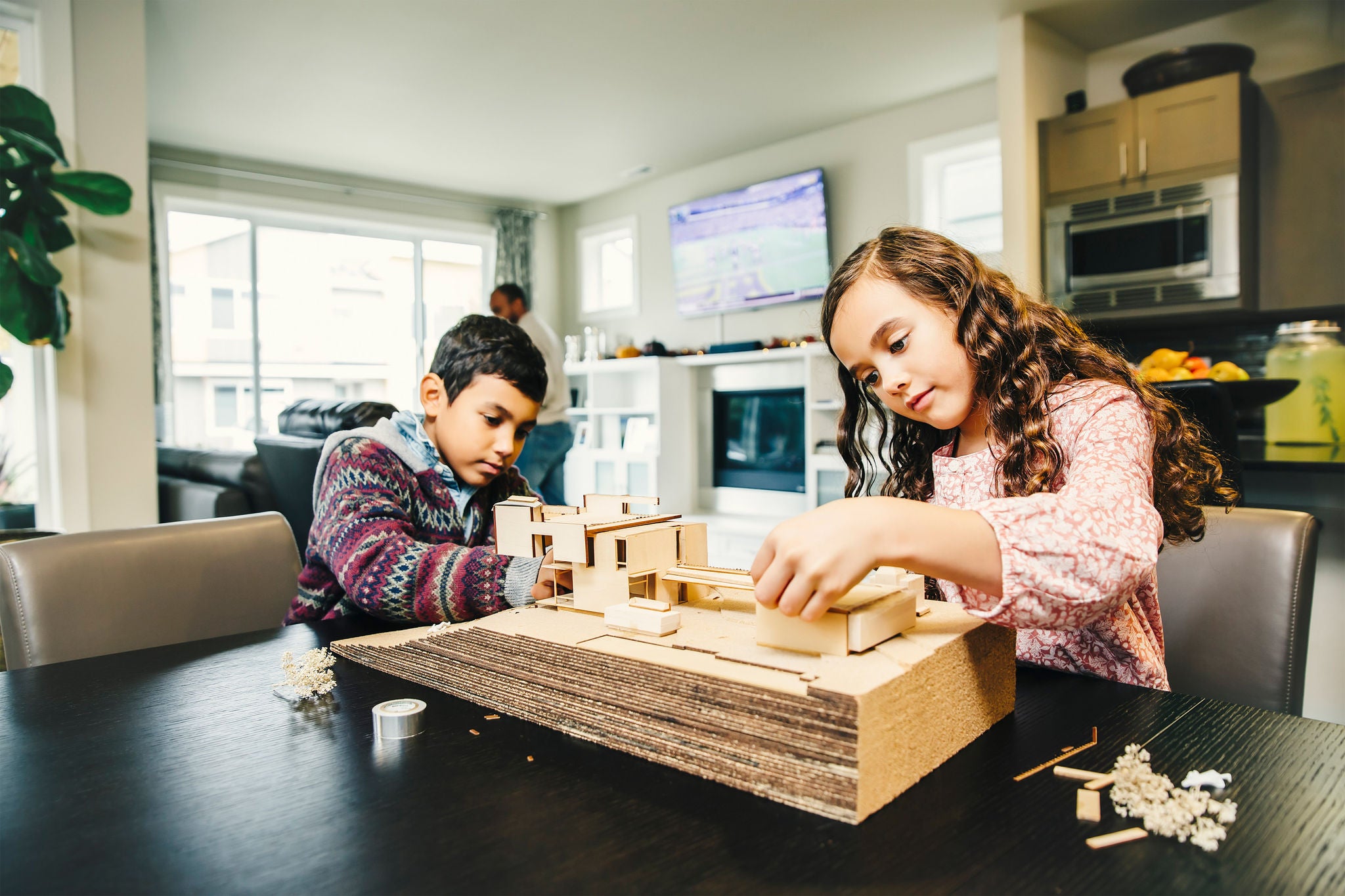 Children building a wooden model at a table indoors