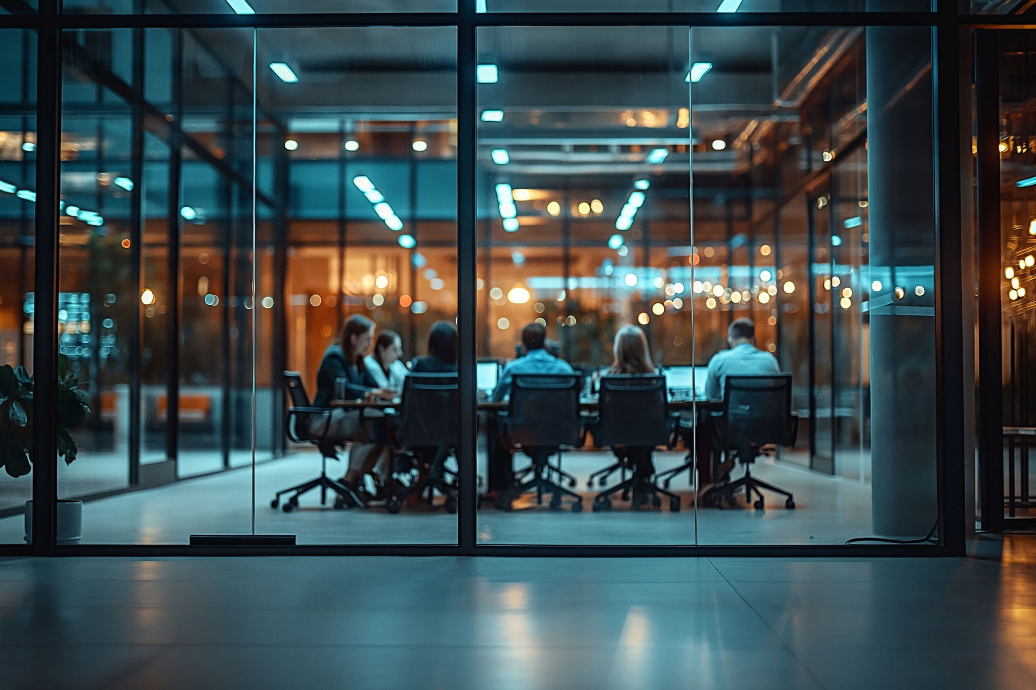 A group of people are sitting in a conference room with a large window. 
