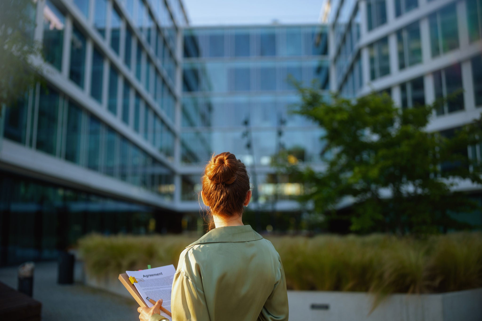 Woman standing in front of glass office building.