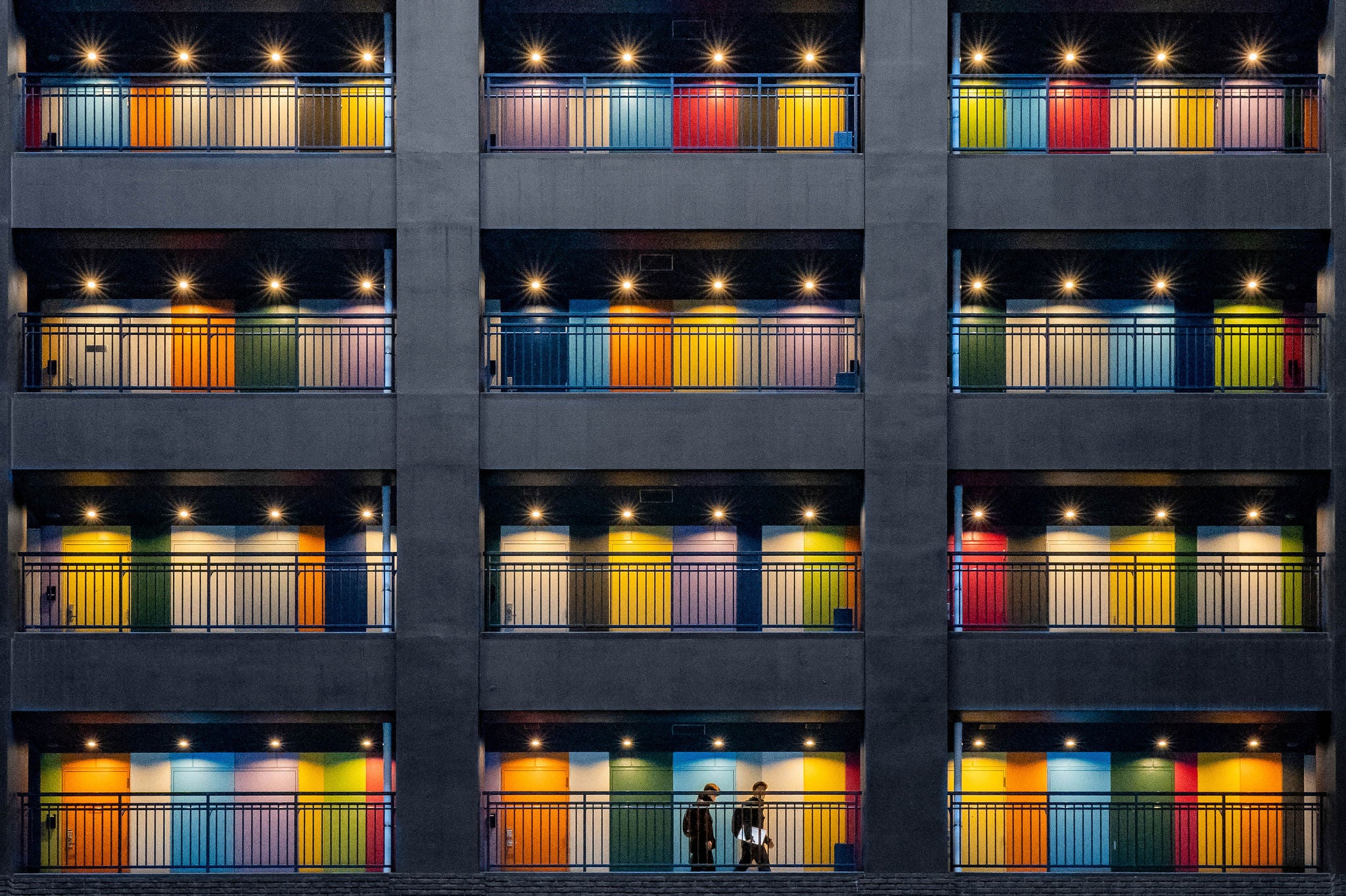 People walking past lit colorful balconies