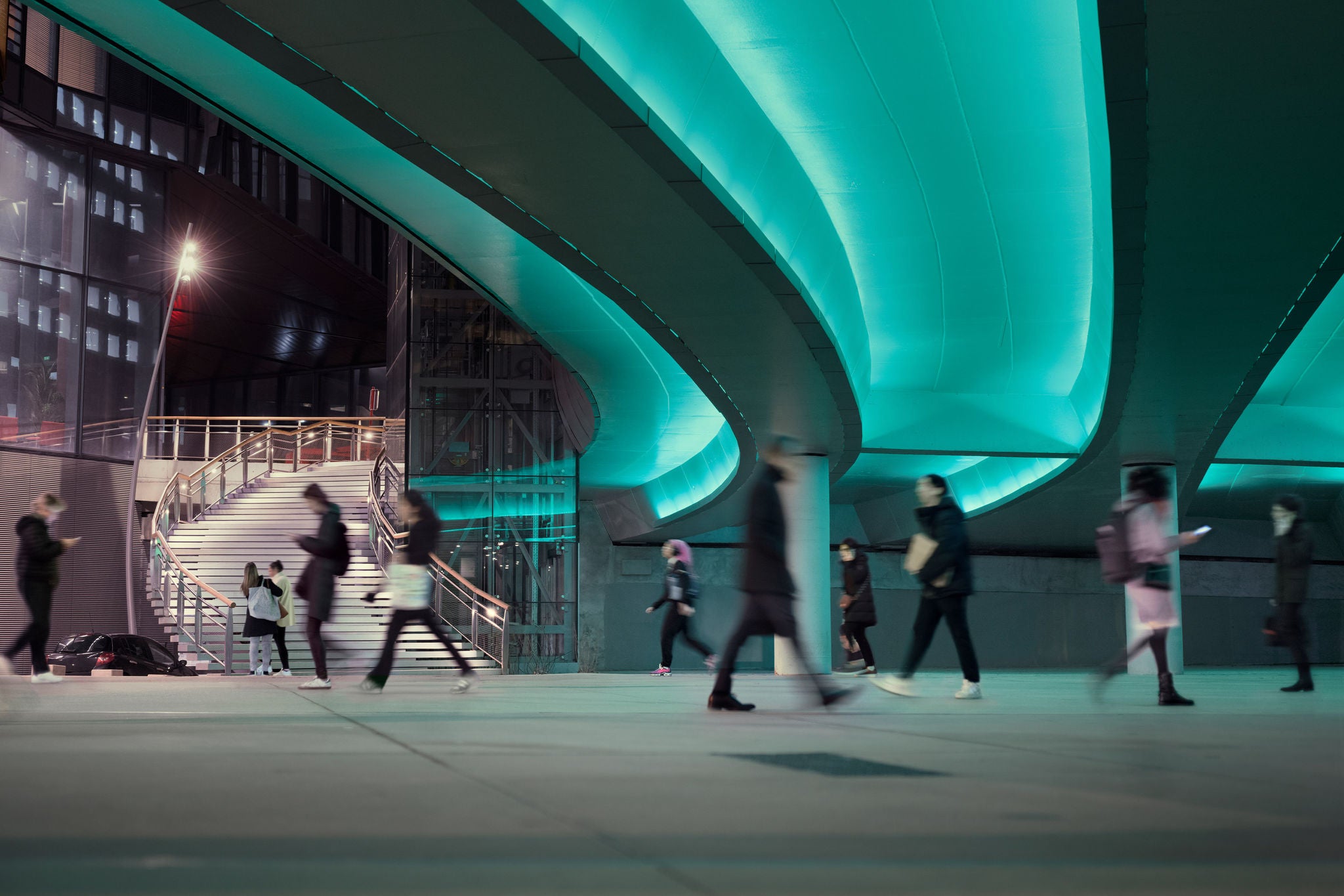 Evening commute with people passing a led illuminated viaduct