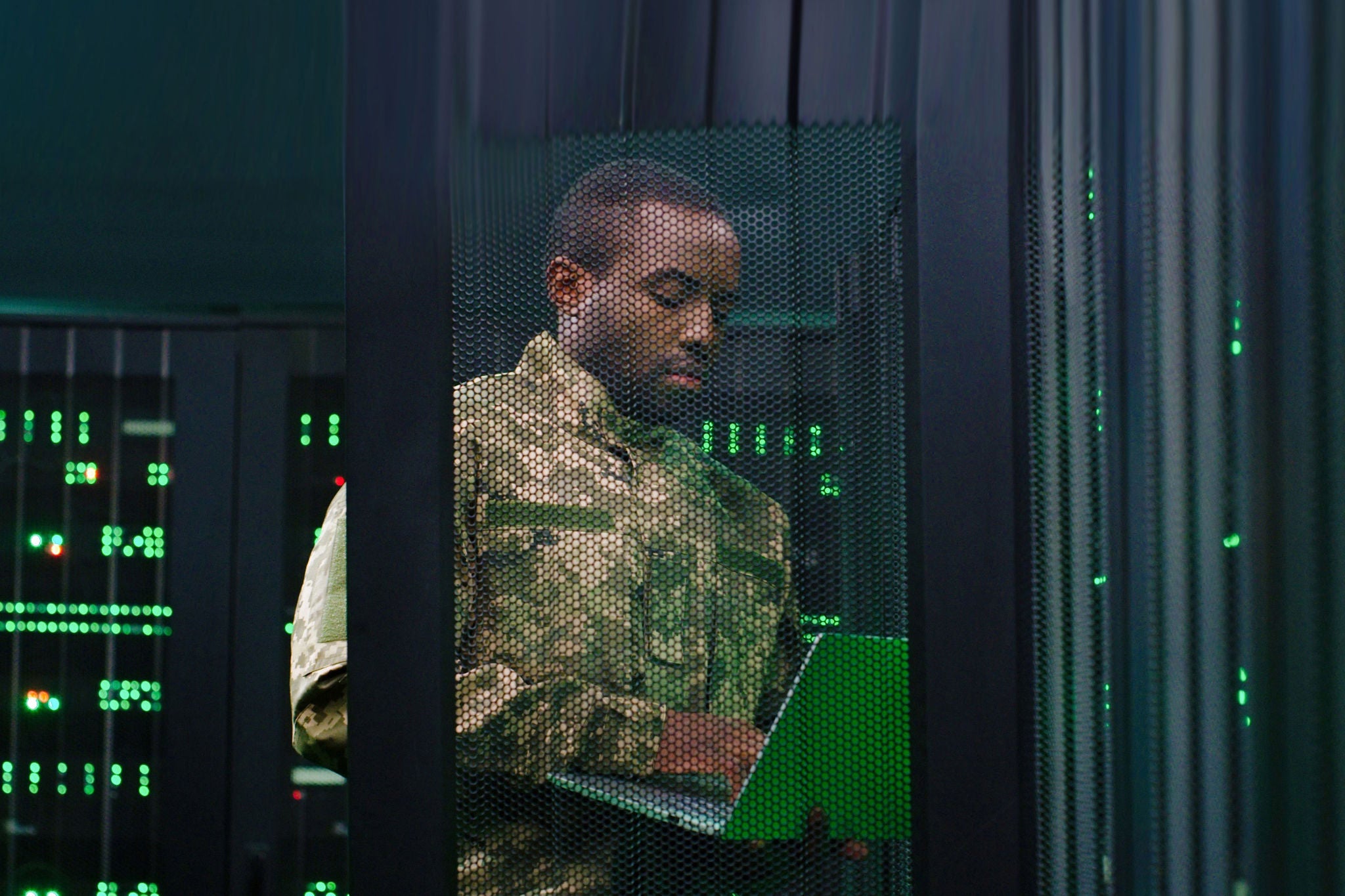 African Americam army man in camouflage costume opening server and controlling. Male typing on laptop computer and checking data in control center. Work at secret information in army. Digital concept.
