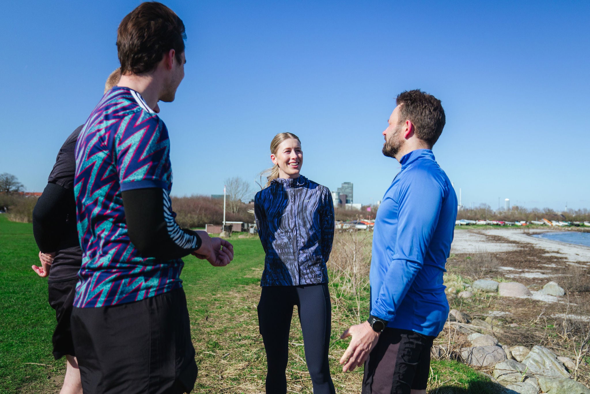 Colleagues stand together outdoors, talking during a casual group activity near the water.
