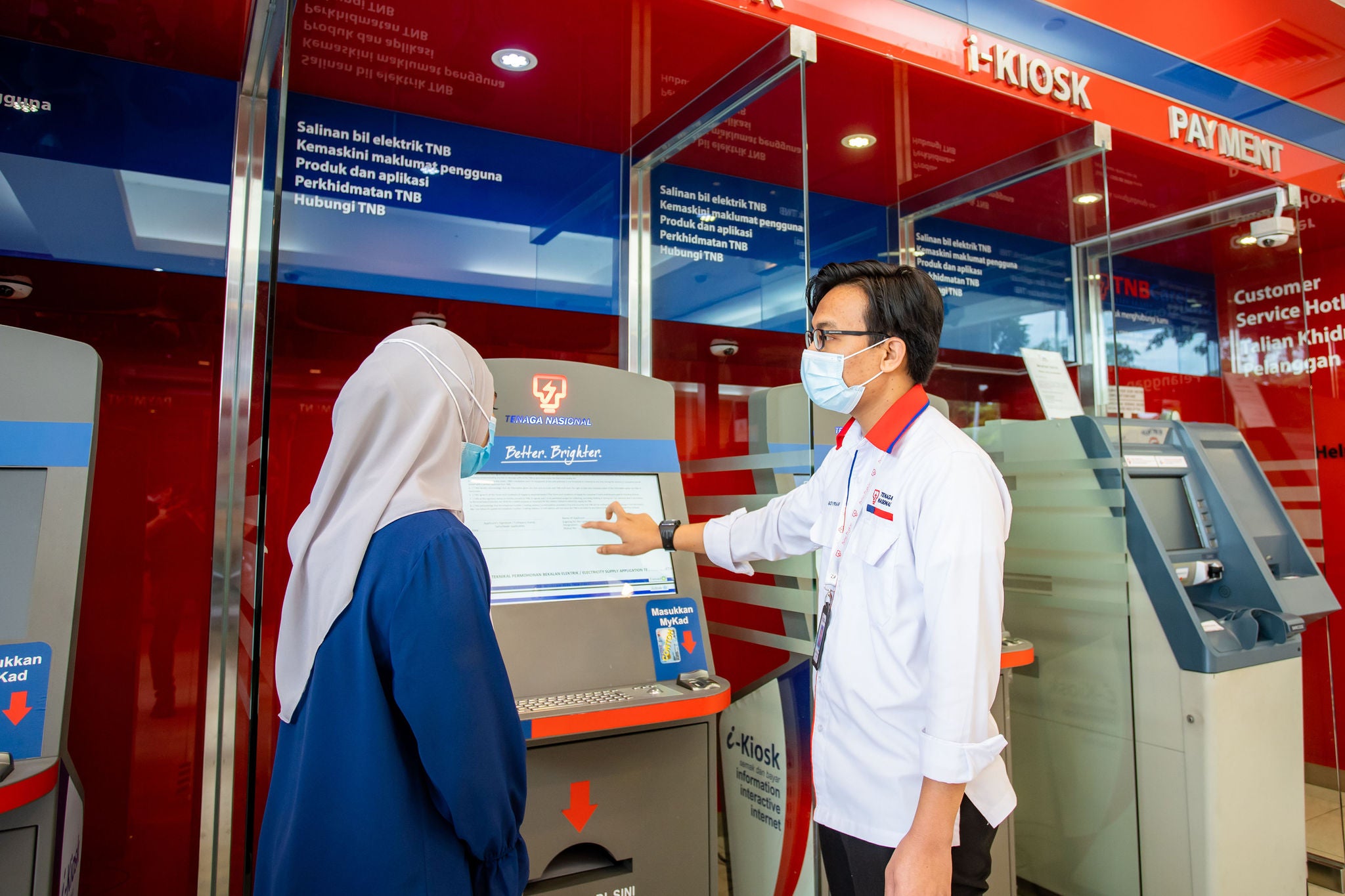 Member of Tenaga staff shows customer an i-Kiosk