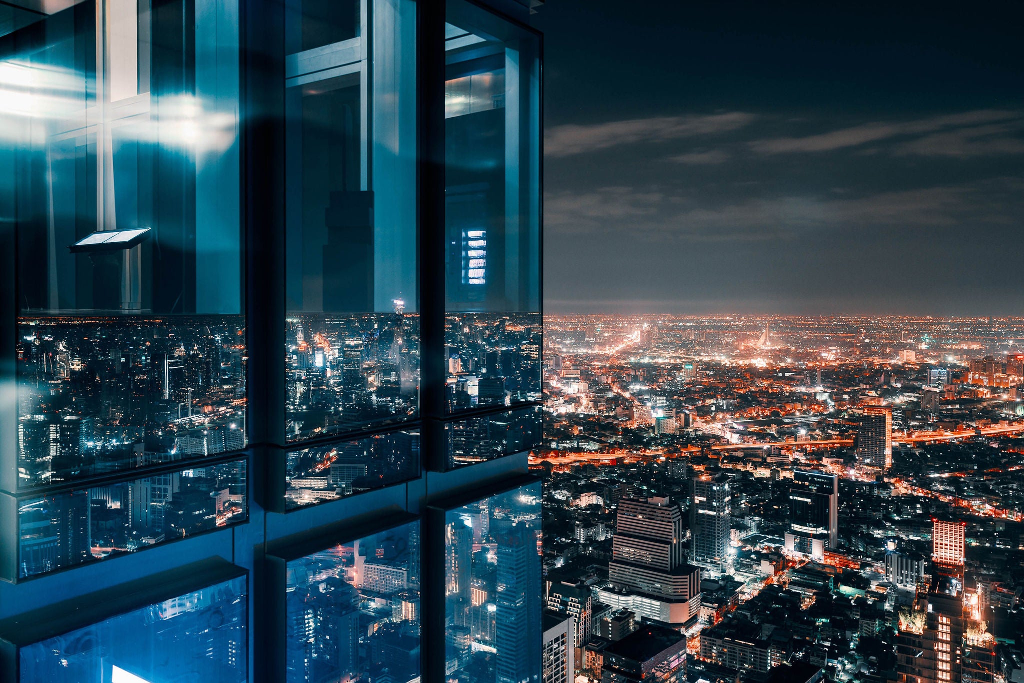 Uitzicht vanuit een glazen kantoorraam op een verlichte skyline bij nacht