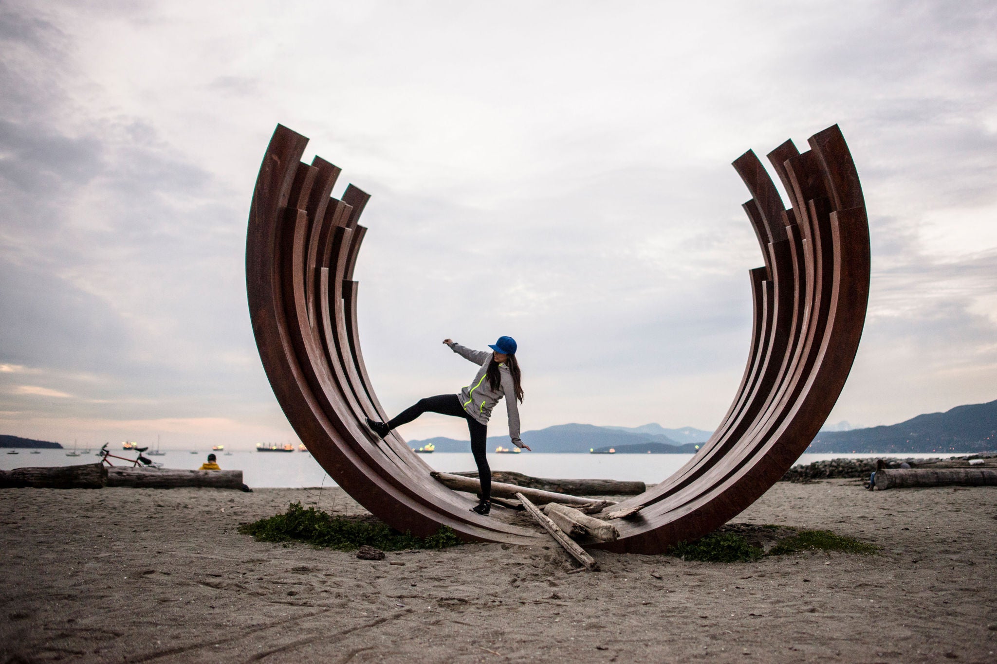 woman standing on arc sculpture, English bay, Vancouver, Canada