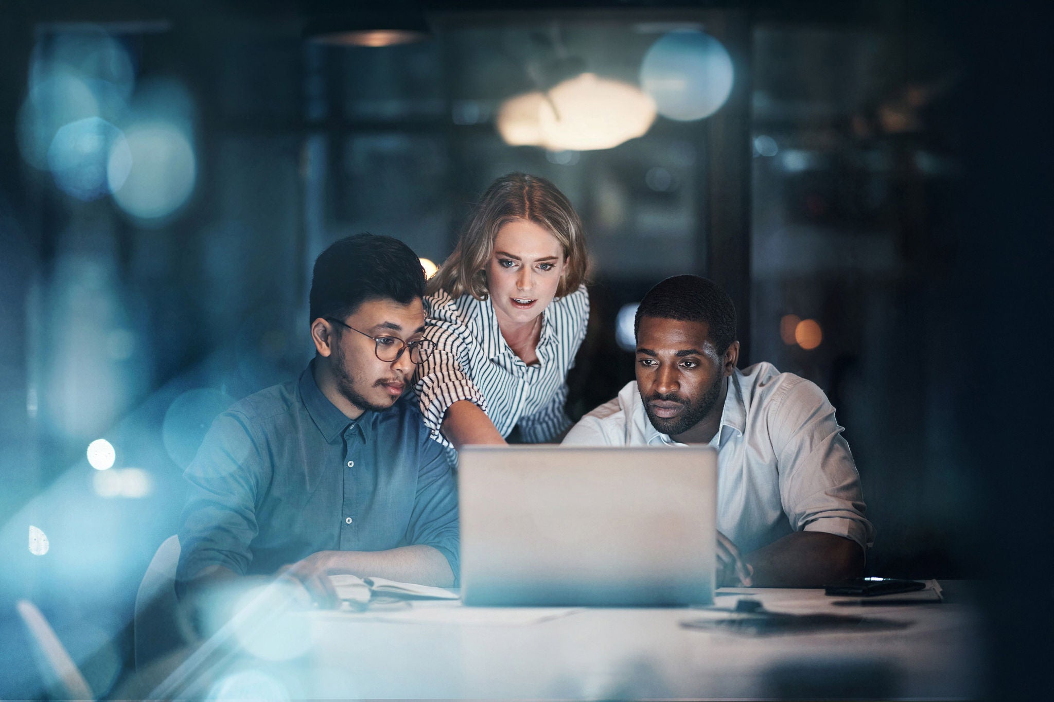Three young business people working together in their office late at night
