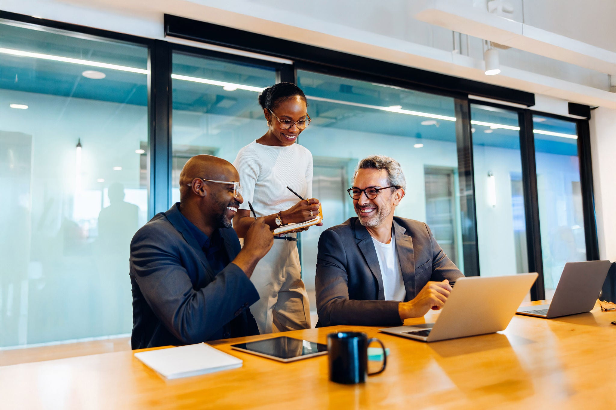 Three cheerful colleagues, two men and one woman, professionally collaborating