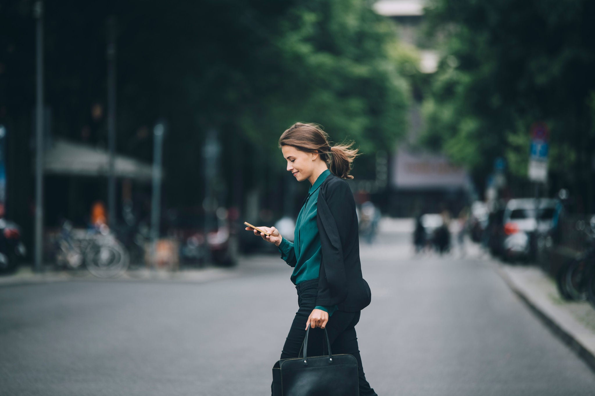 Side view of young woman using phone on road