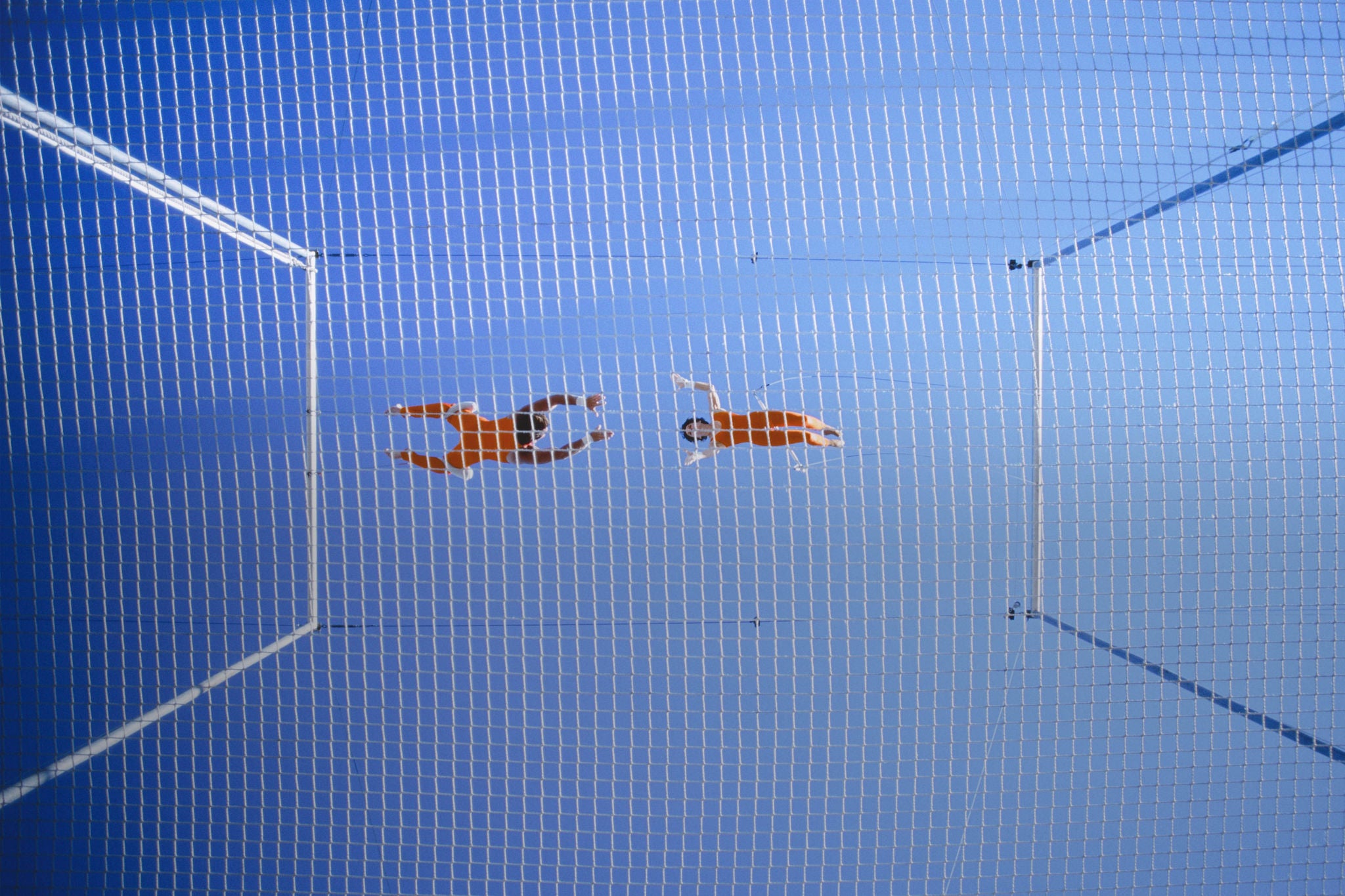 Two trapeze artists performing release move