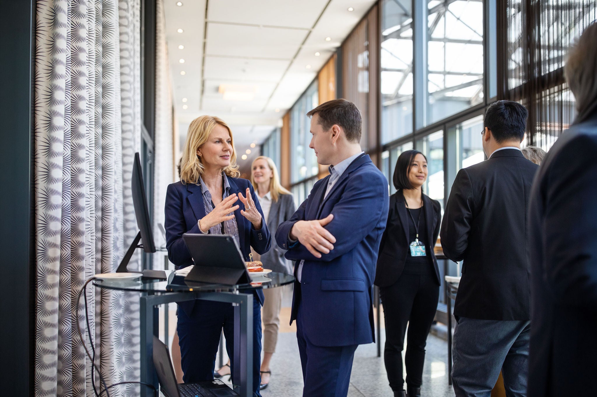 Business professionals networking and conversing at a modern office corridor.