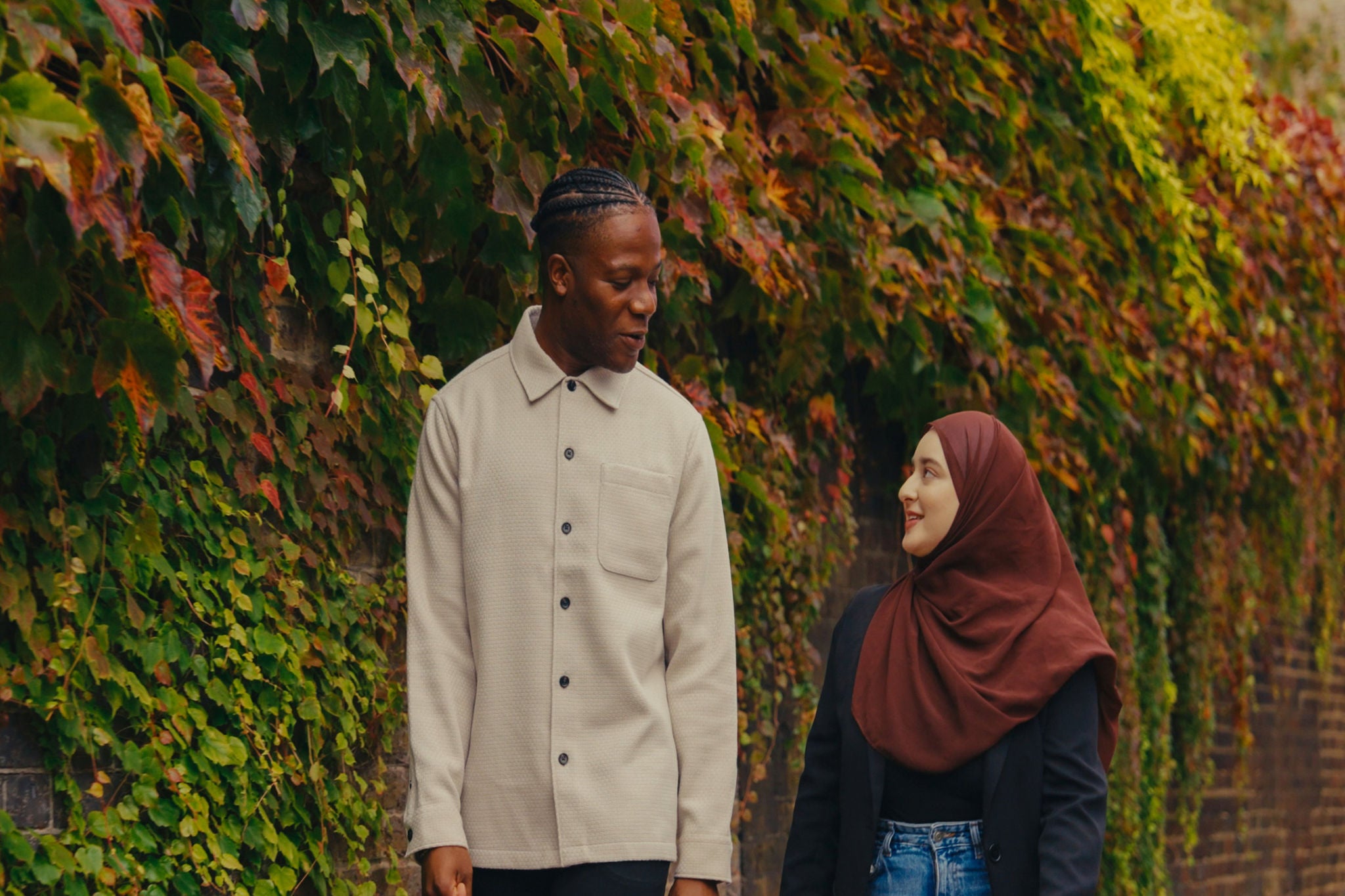 Two people outdoors beside vibrant autumn foliage