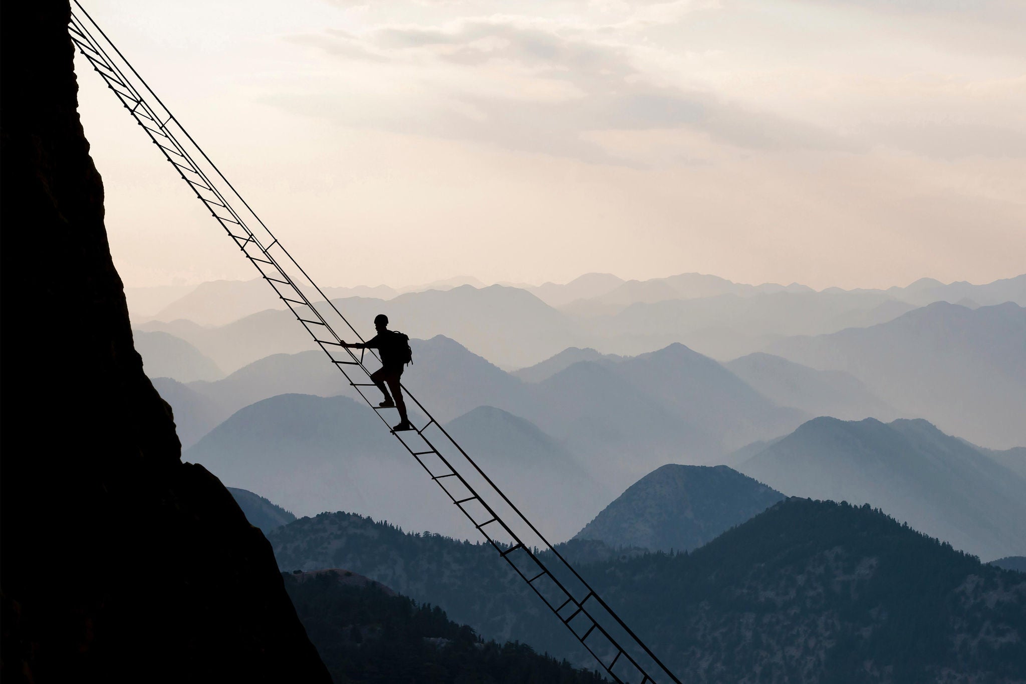 Bergsteiger kletter eine Leiter vor Bergkulisse hinauf
