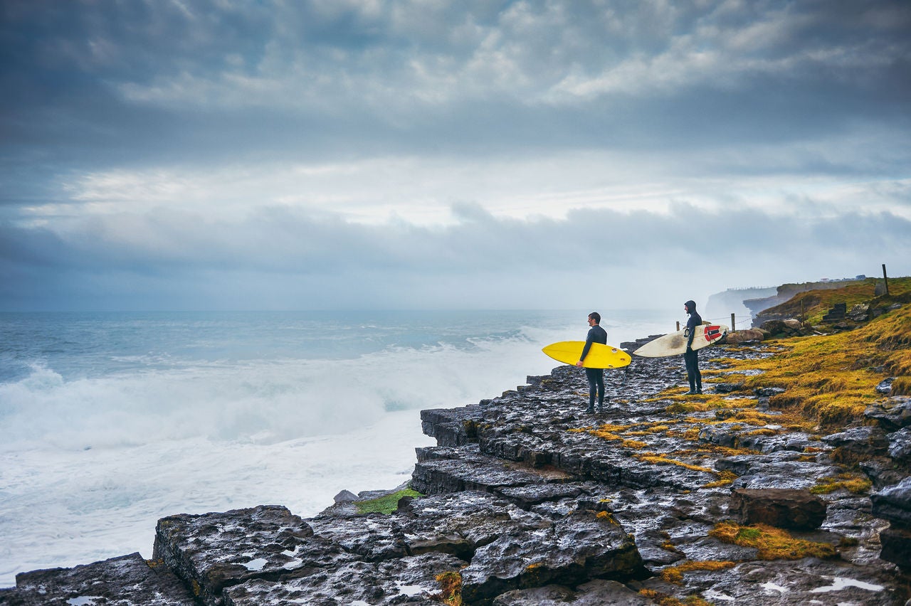 衝浪者站在懸崖上，眺望著風暴中的海洋。