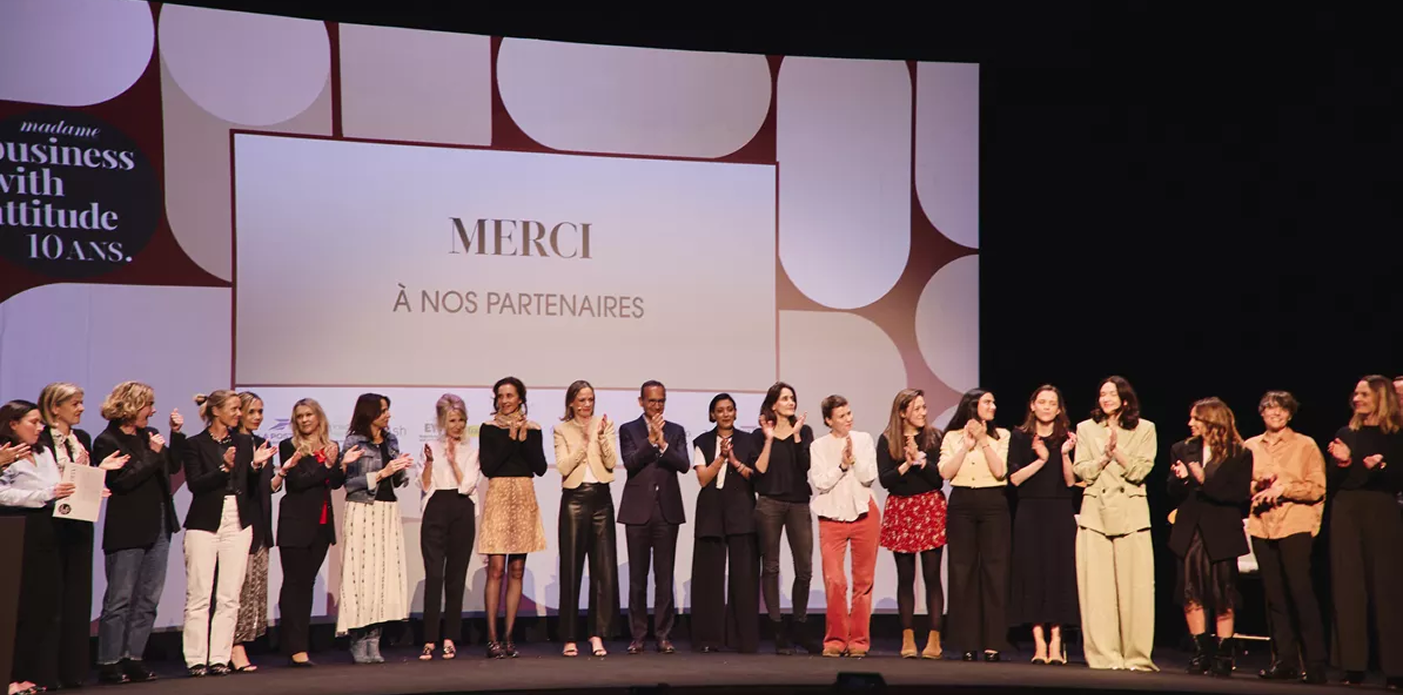 Participants sur scene applaudissant sous ecran merci a nos partenaires