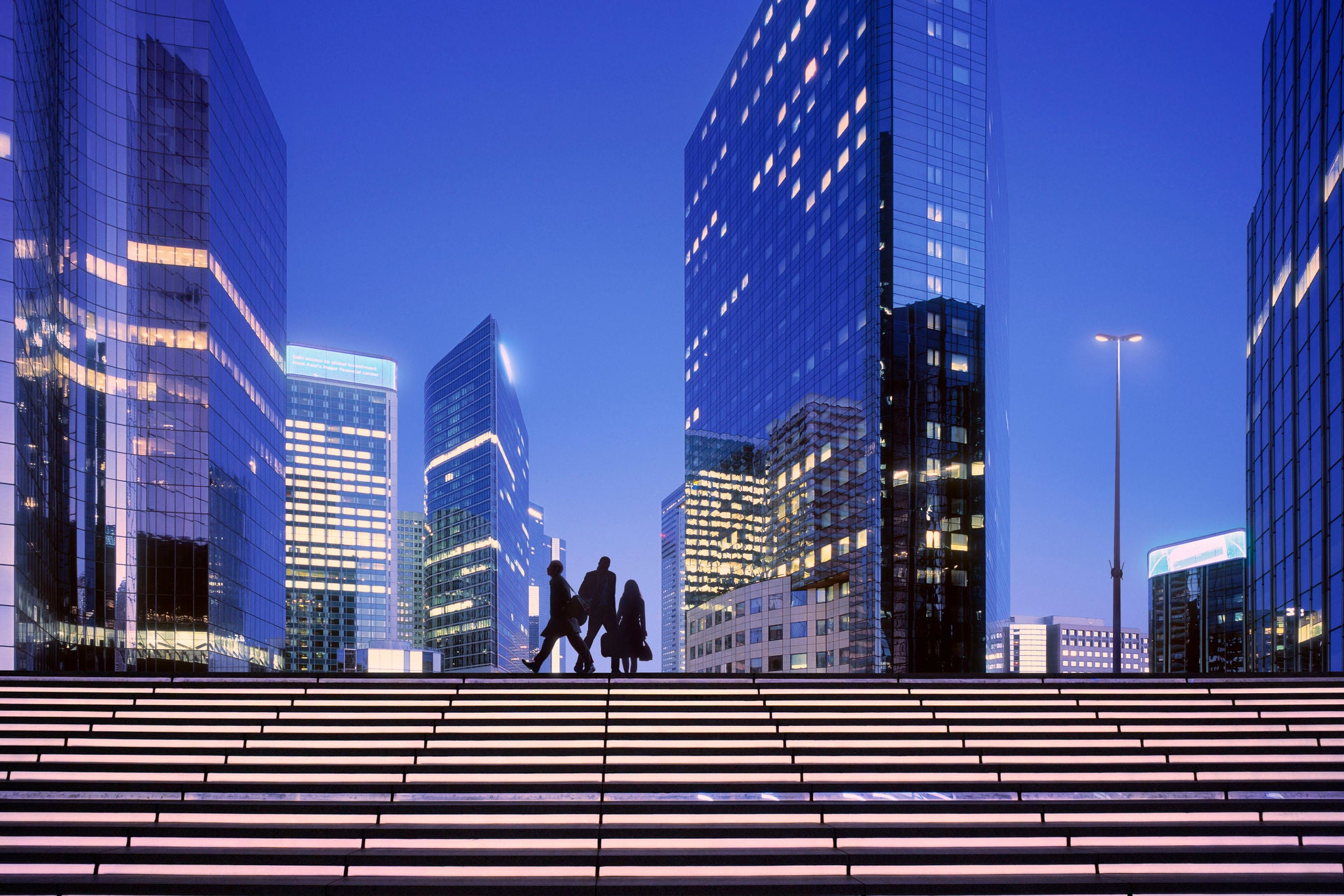 Morning image with businesswoman and businessmen arriving at modern business district.