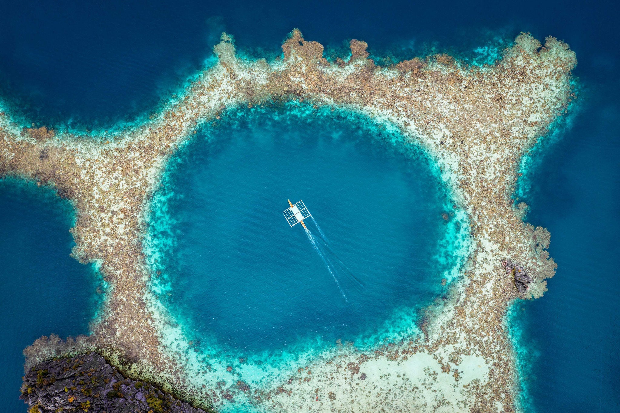Aerial view of bangka boat sailing over coral reef in Palawan, Philippines