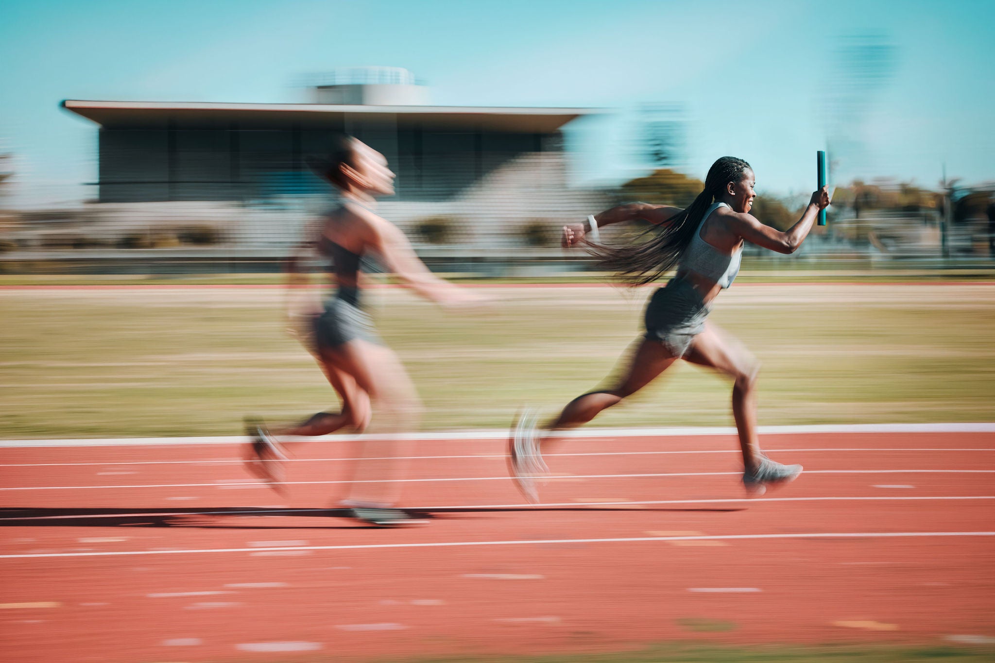 two women running relay sprint in competition